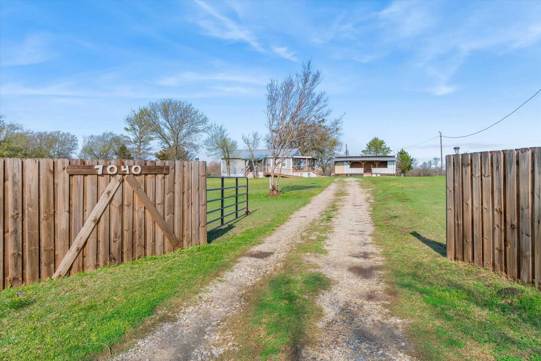 View of dirt / gravel driveway featuring a gate and a gated entry
