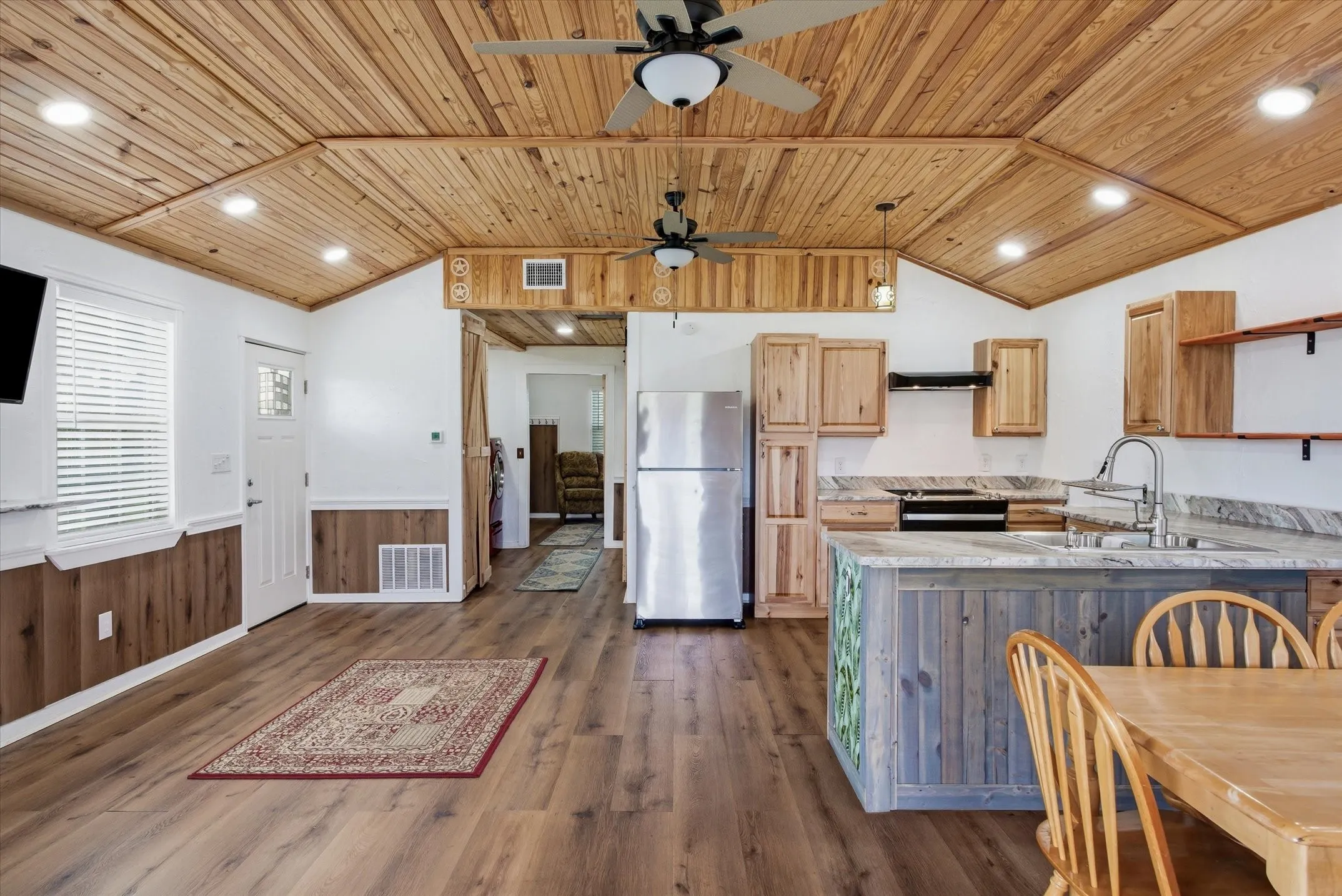 Kitchen with light countertops, a wainscoted wall, light wood finish cabinetry, recessed lighting, and freestanding refrigerator