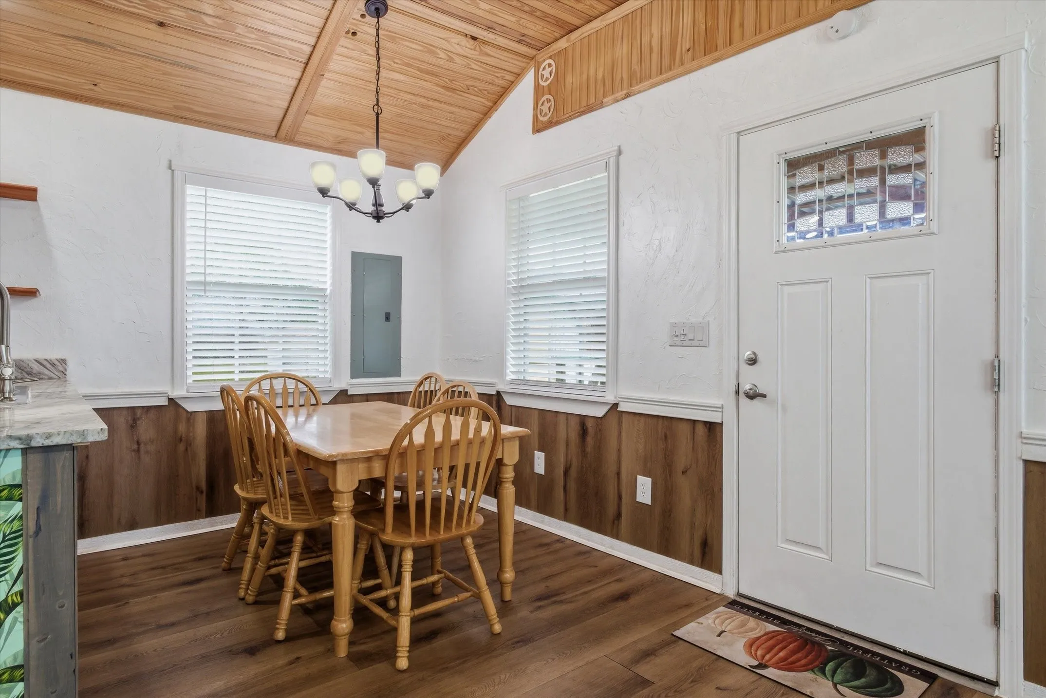 Dining room featuring wooden walls, wainscoting, a vaulted wooden ceiling, dark wood-type flooring, and hanging lights