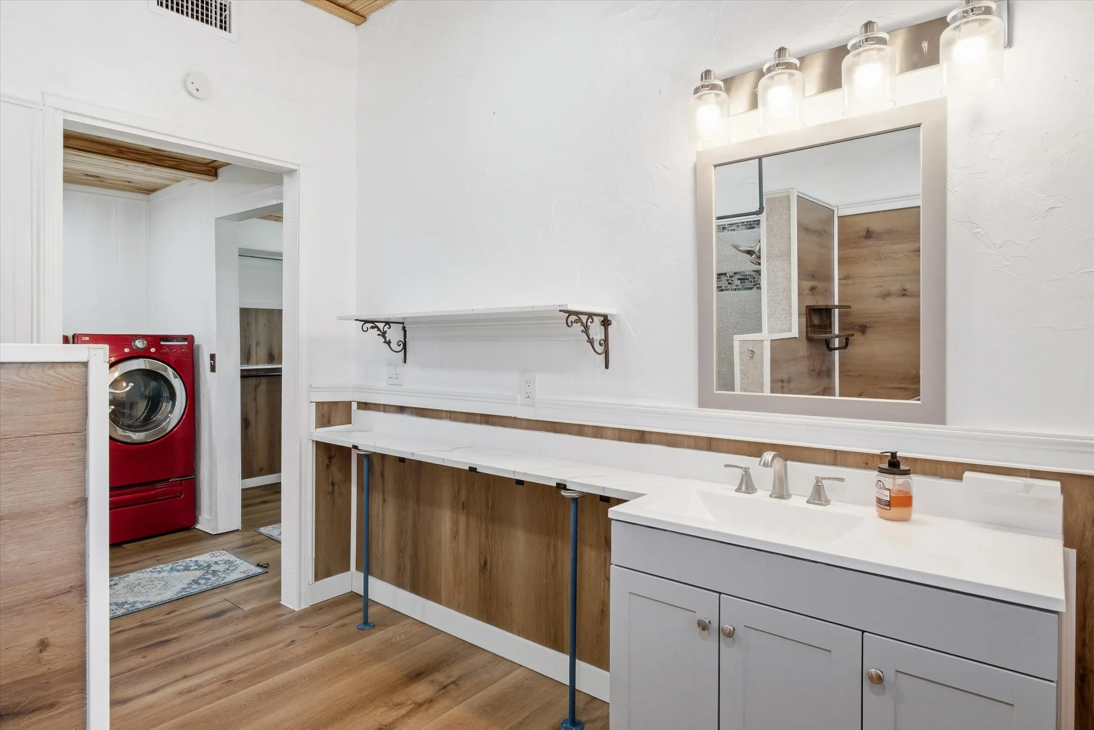 Bathroom with vanity, light wood-style floors, and washer / dryer