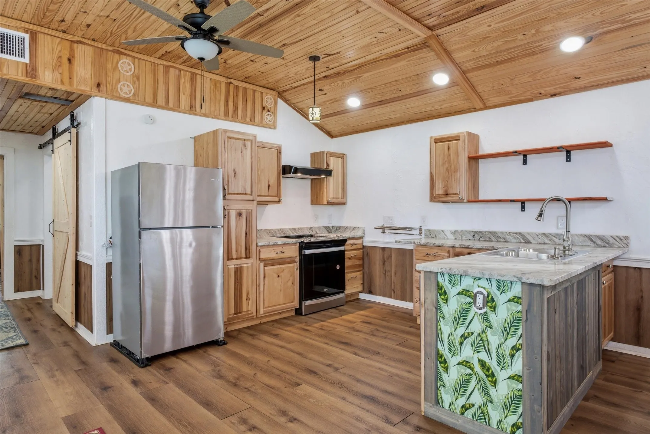 Kitchen featuring stainless steel appliances, a peninsula, a vaulted wood ceiling, ceiling fan, and a barn door