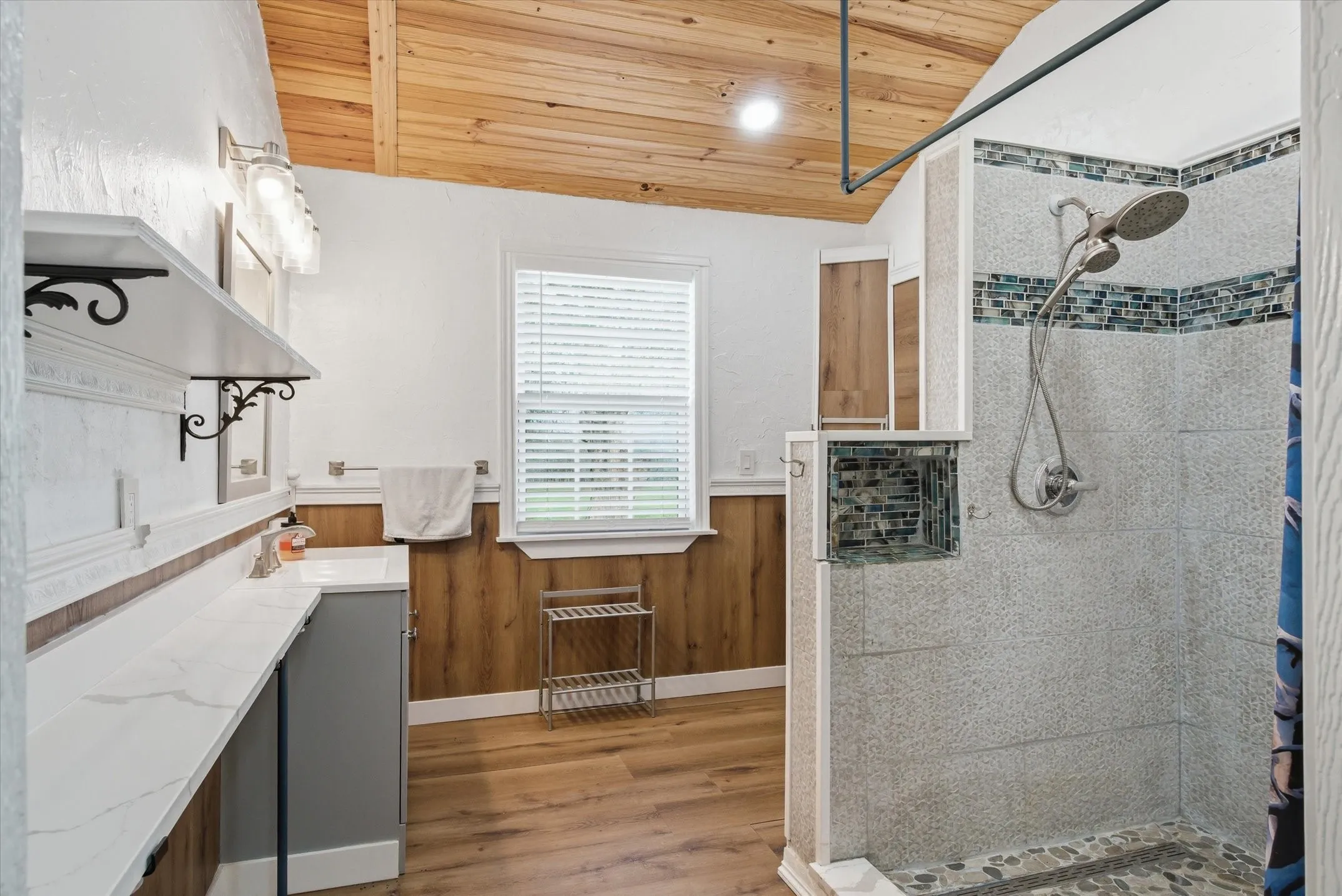 Bathroom featuring a wainscoted wall, vanity, a shower stall, a vaulted wooden ceiling, and wood finished floors