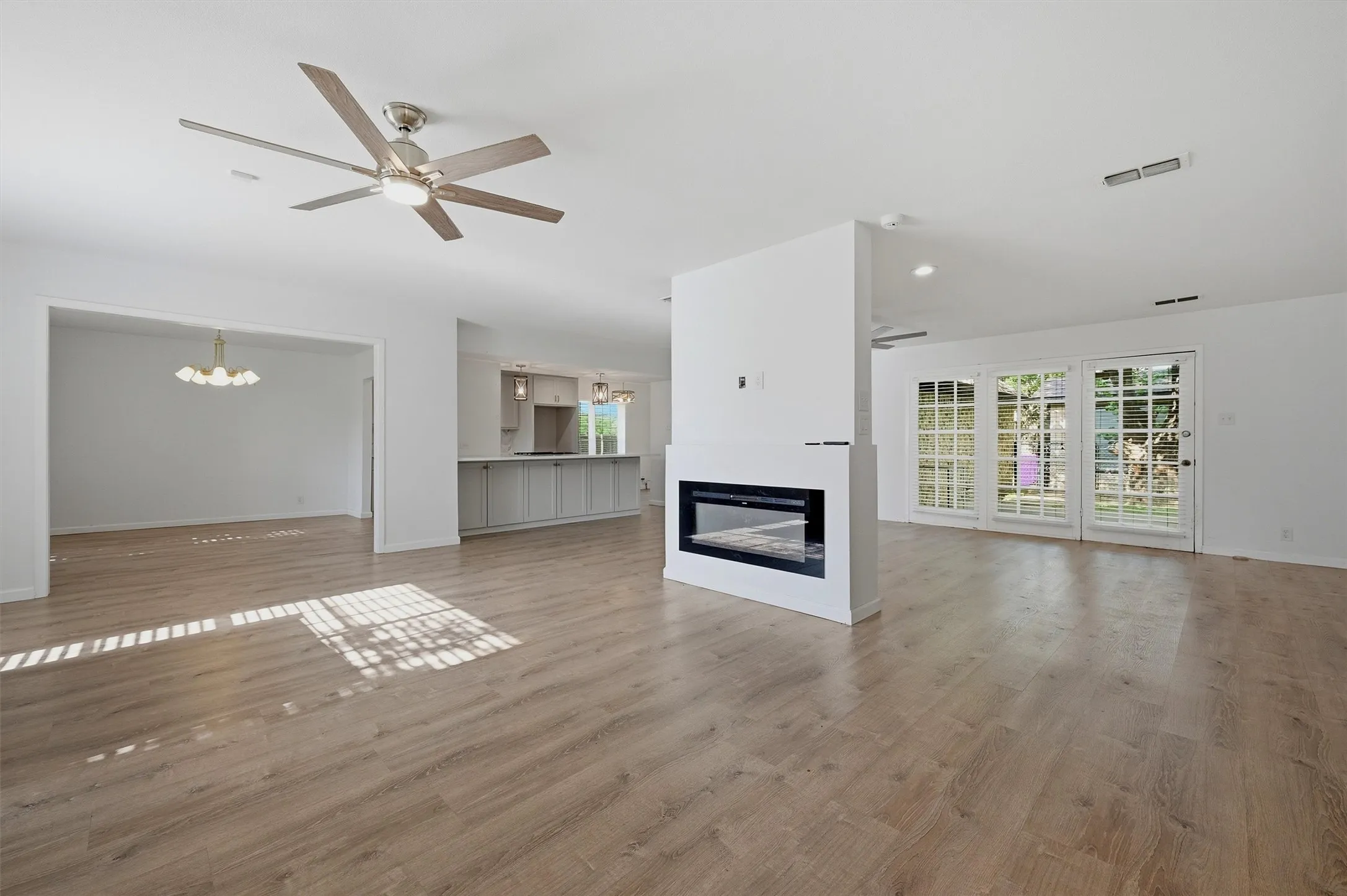 Open-concept living space featuring wood-finish flooring, a contemporary electric fireplace, and multi-pane patio doors