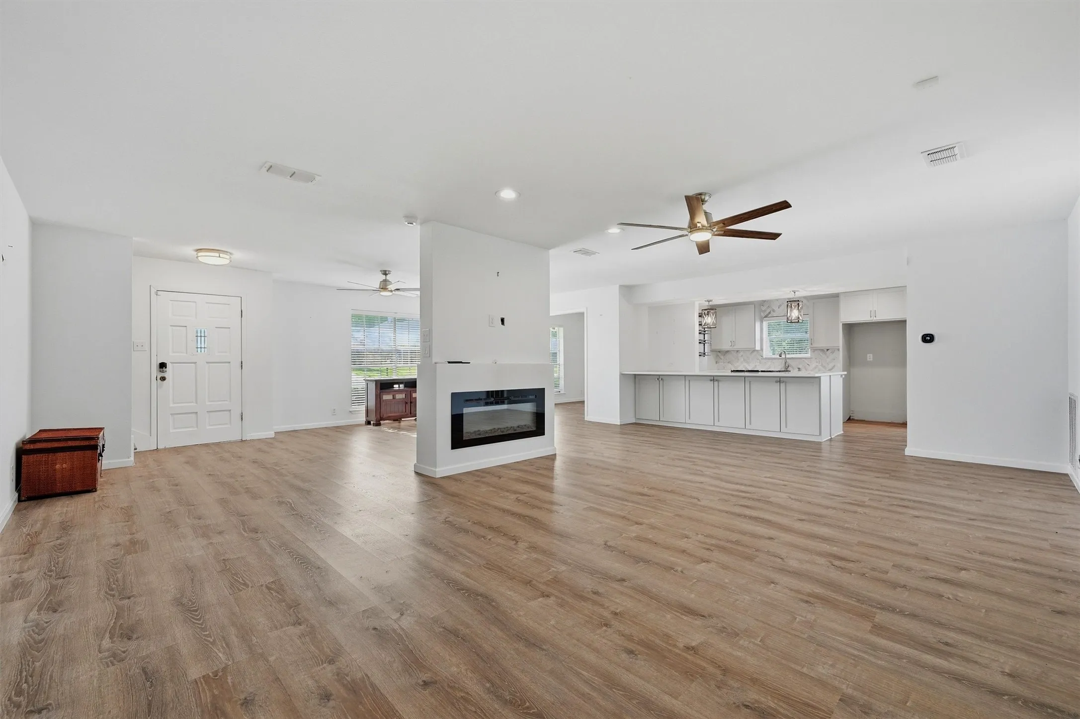 Open-concept living area featuring wood-finish flooring, a contemporary electric fireplace, and recessed lighting