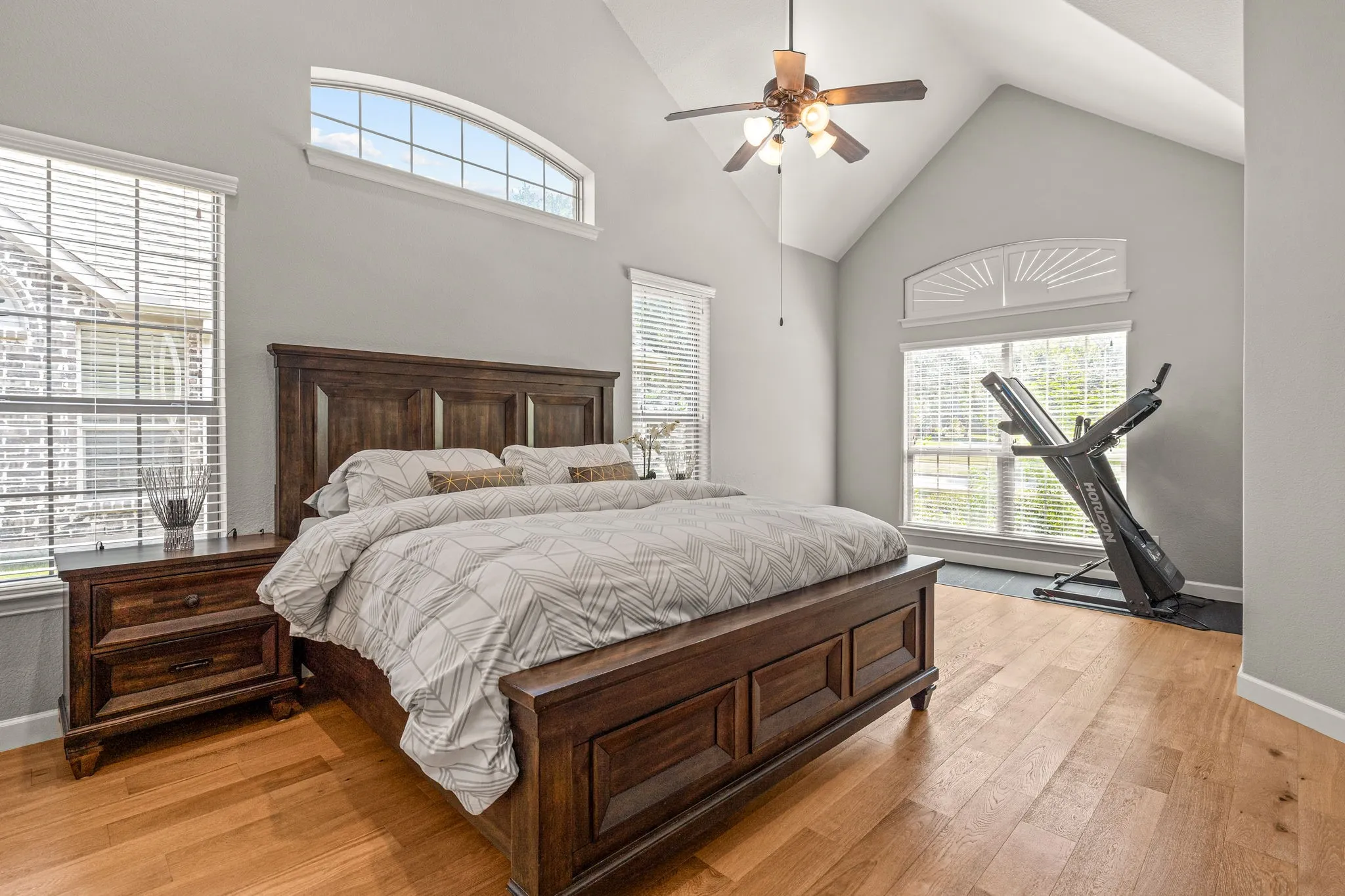Bedroom featuring a high ceiling, ceiling fan, and light wood-style flooring