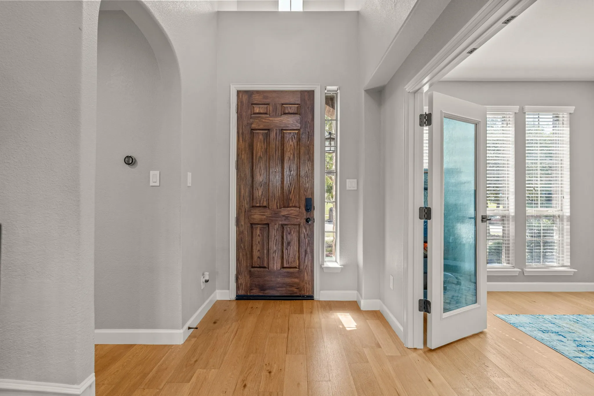 Foyer entrance with light wood-style floors, plenty of natural light, and arched walkways