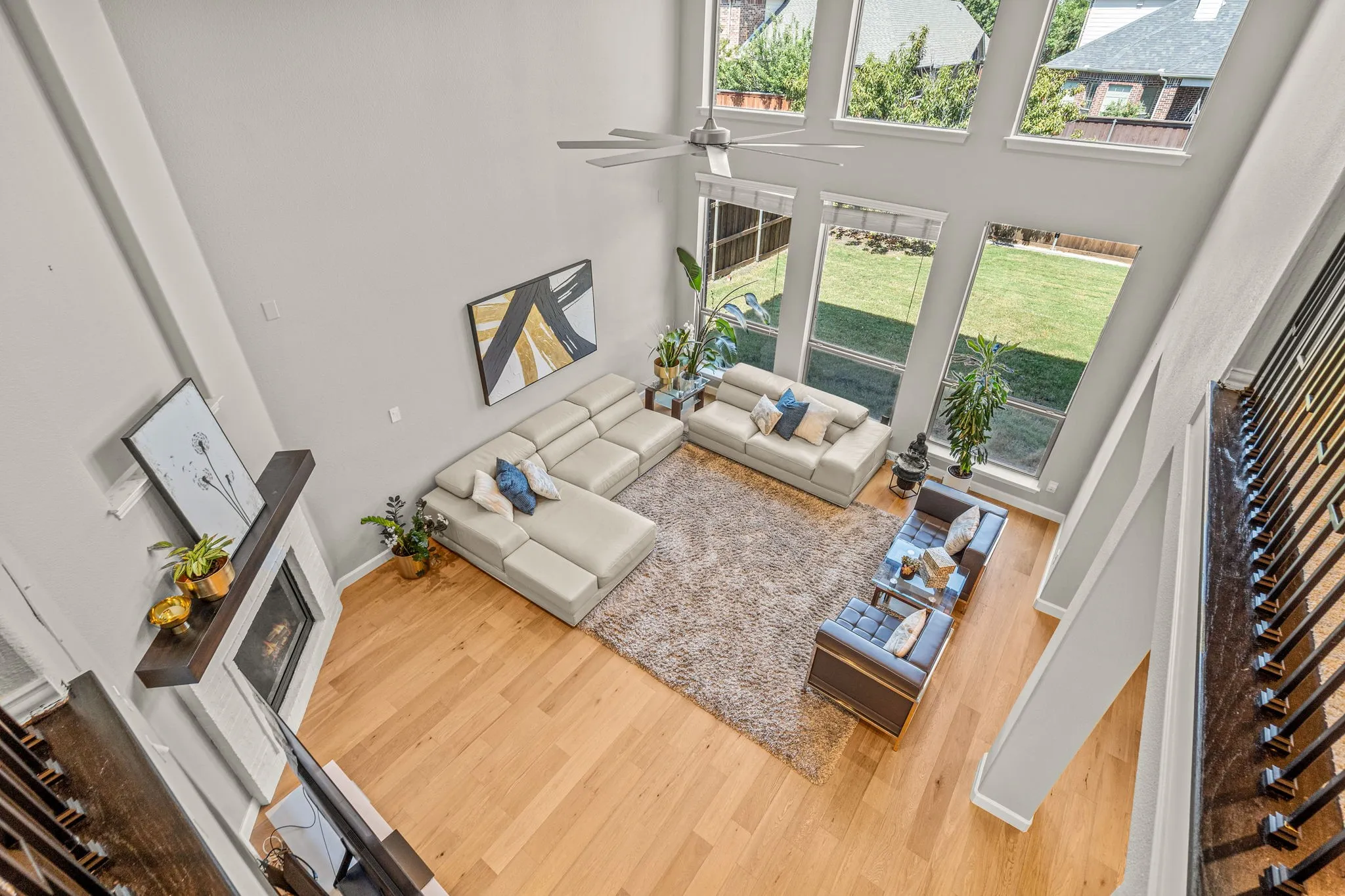Living room featuring a high ceiling, wood finished floors, a glass covered fireplace, and a ceiling fan