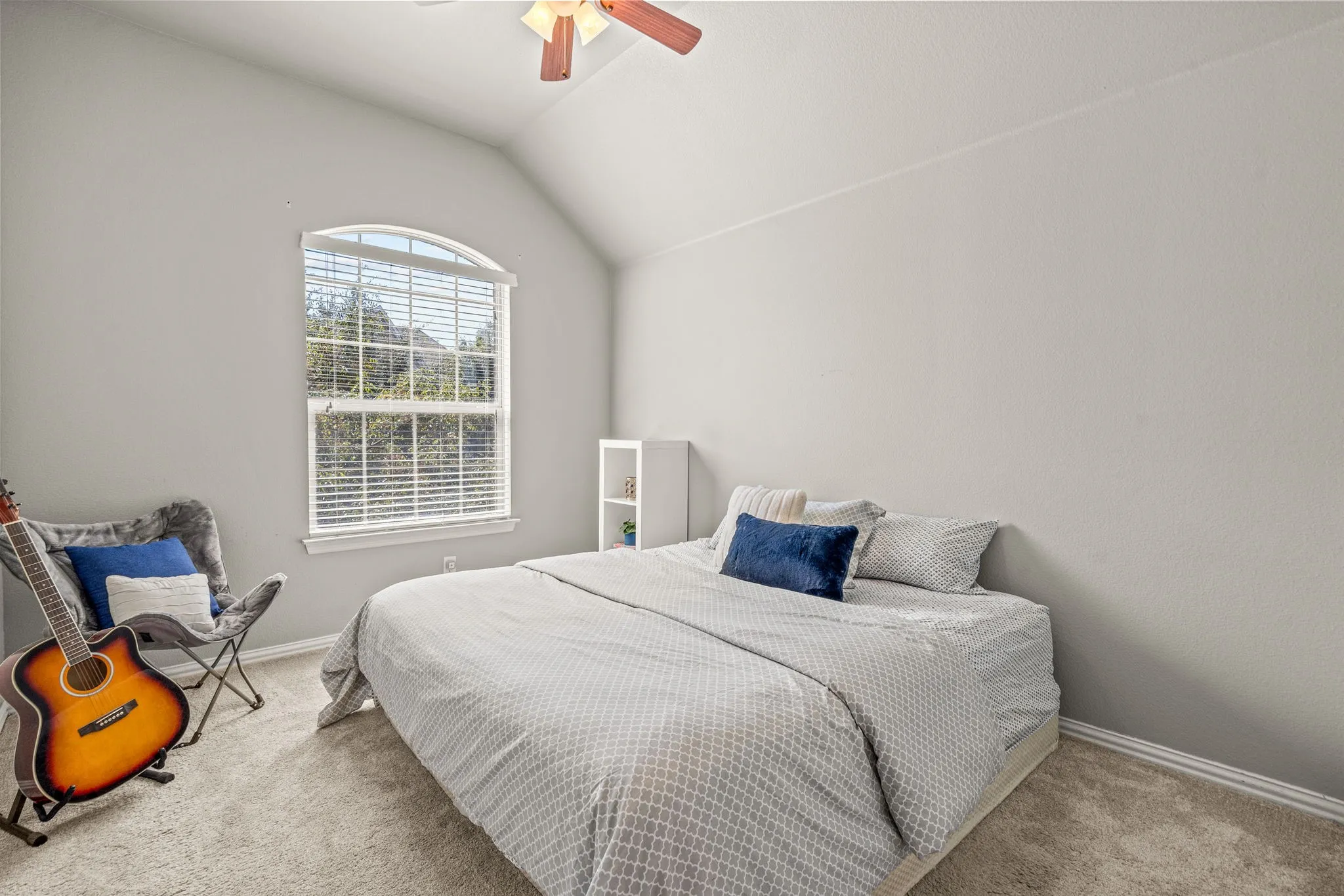 Carpeted bedroom with a ceiling fan and lofted ceiling