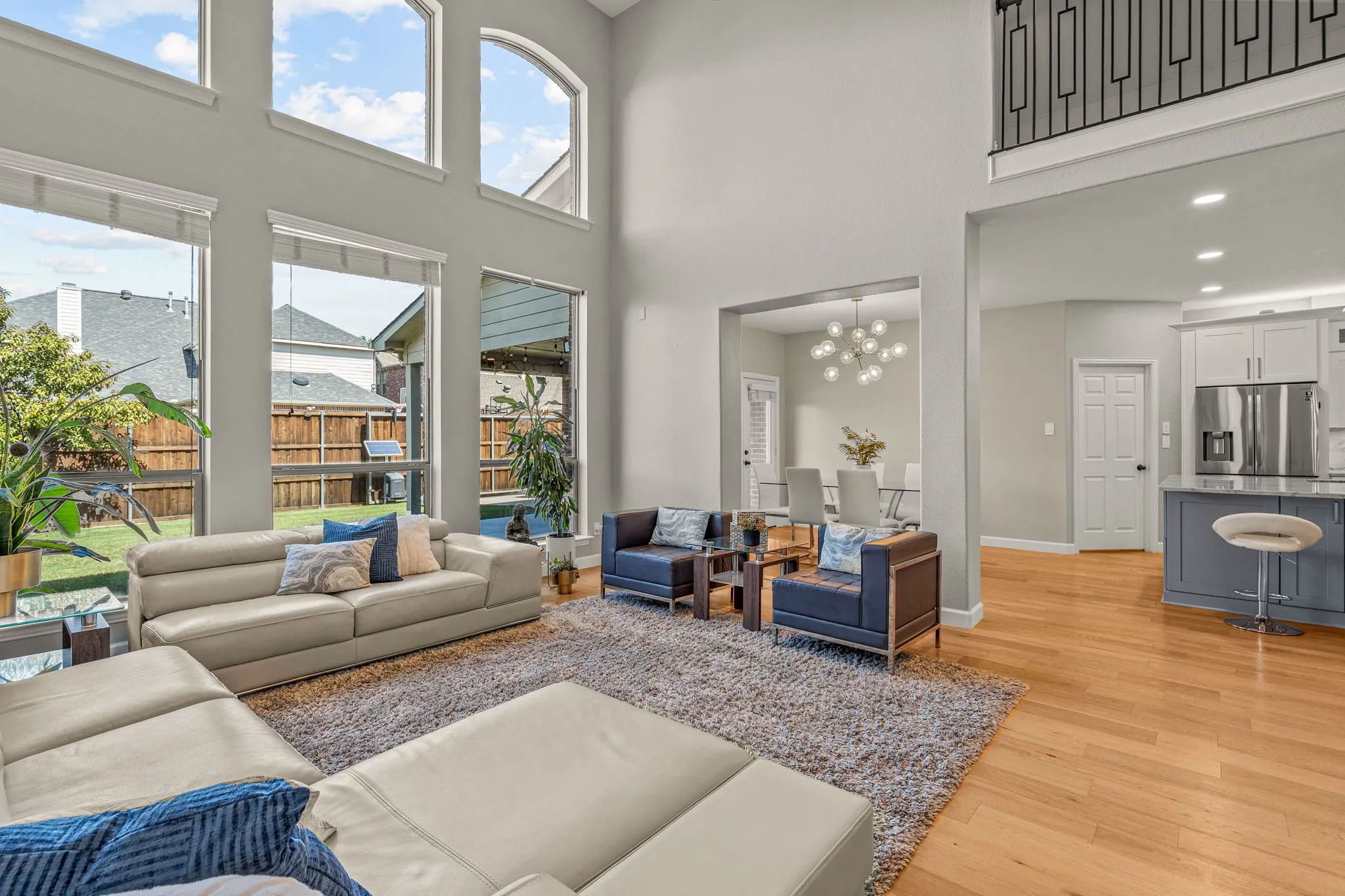 Living area featuring hanging lights, light wood-type flooring, and a high ceiling