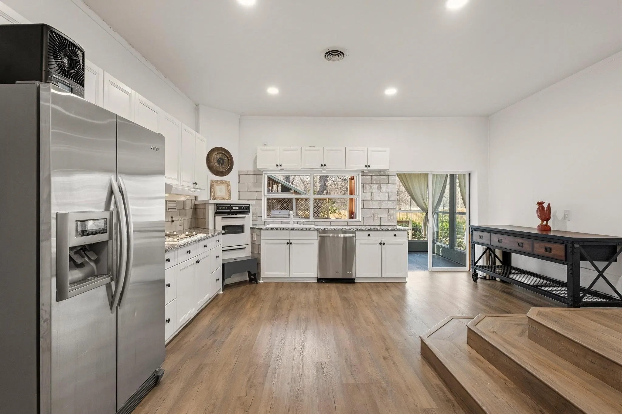 Kitchen with stainless steel appliances, white cabinetry, recessed lighting, dark wood finished floors, and backsplash