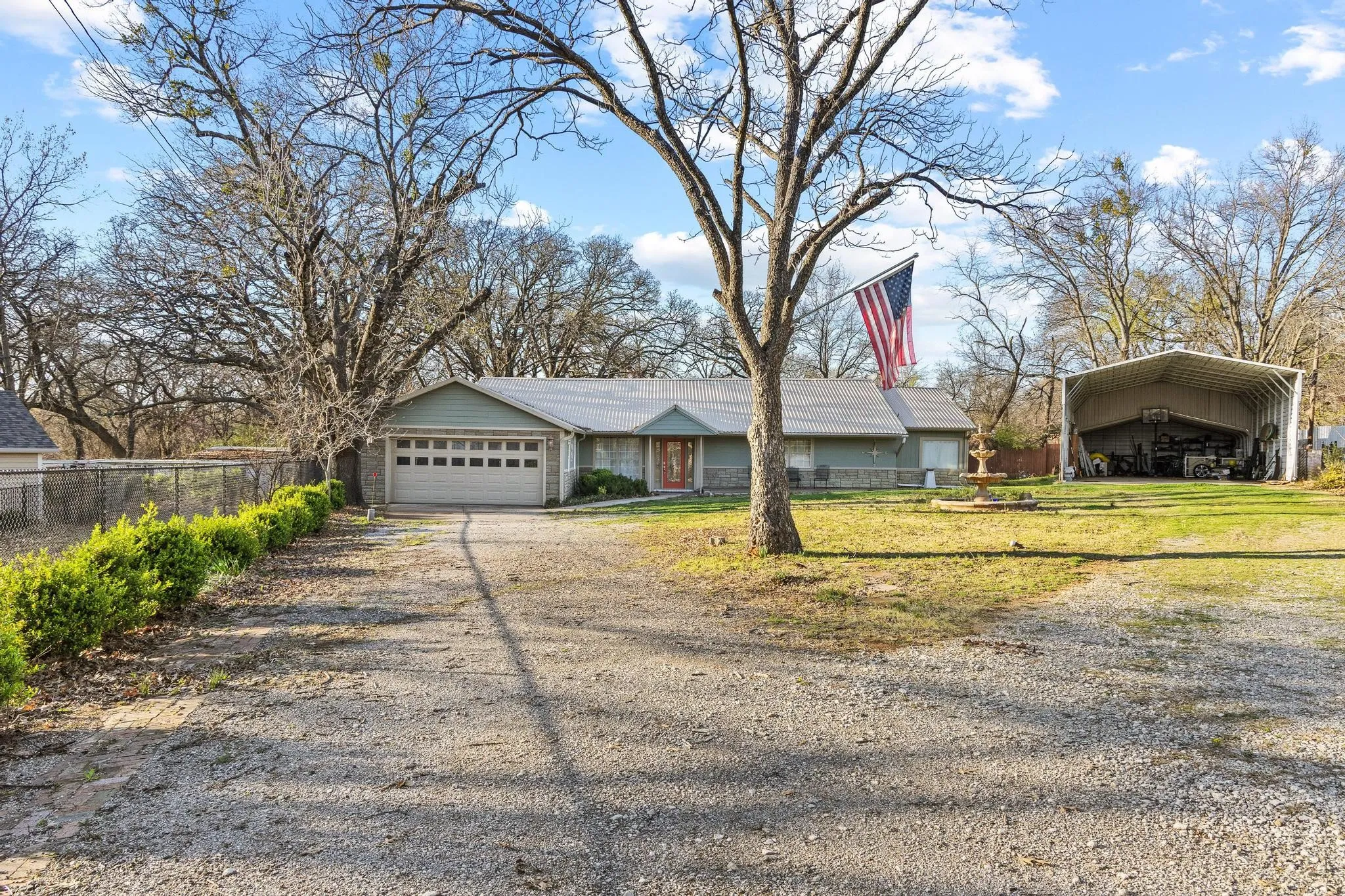 Ranch-style residence featuring a two-car garage, gravel driveway, and a large metal outbuilding