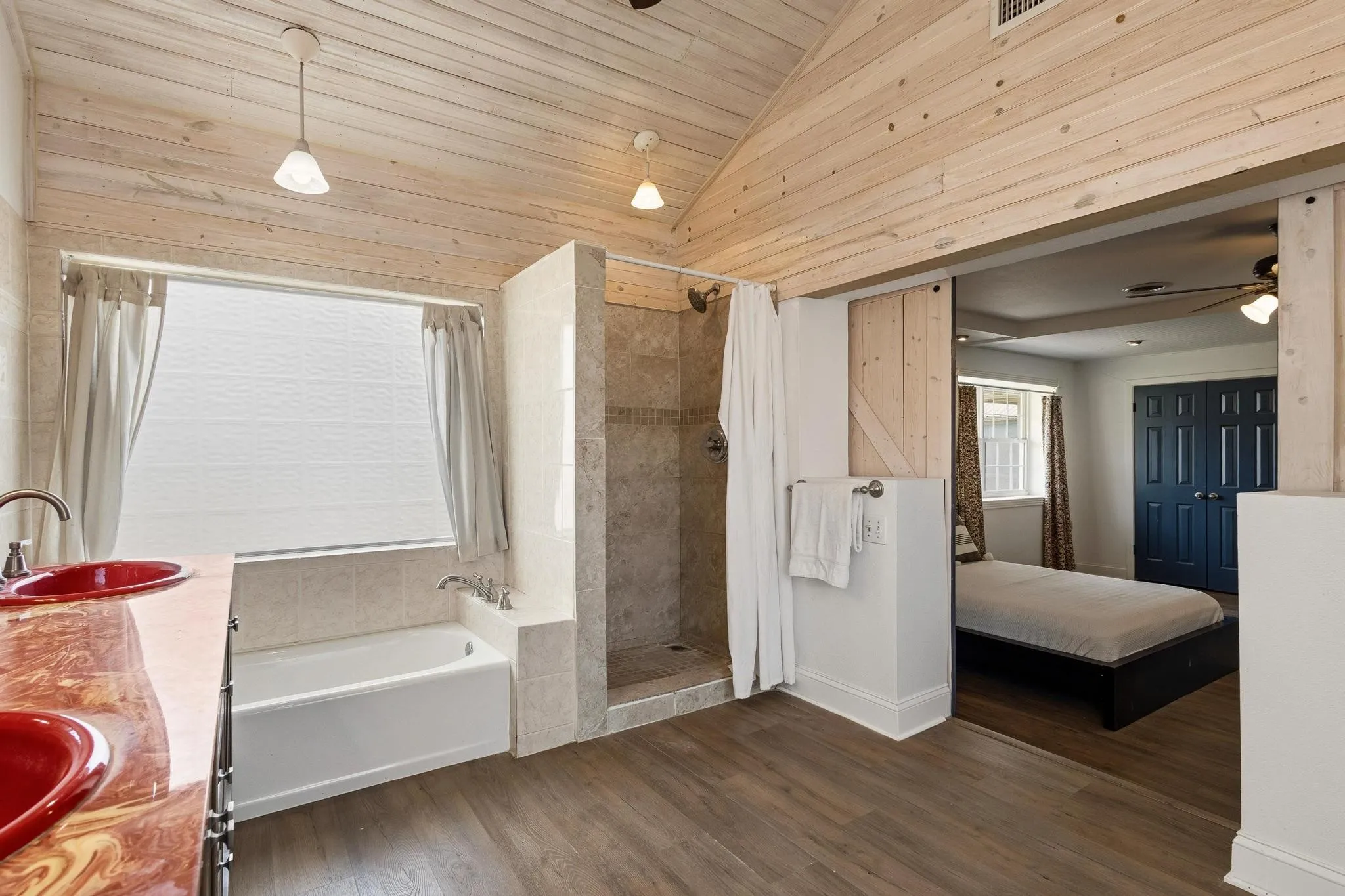 Primary ensuite bathroom with double vanity, dark wood-type flooring, a garden tub, a shower stall, and a vaulted wood ceiling
