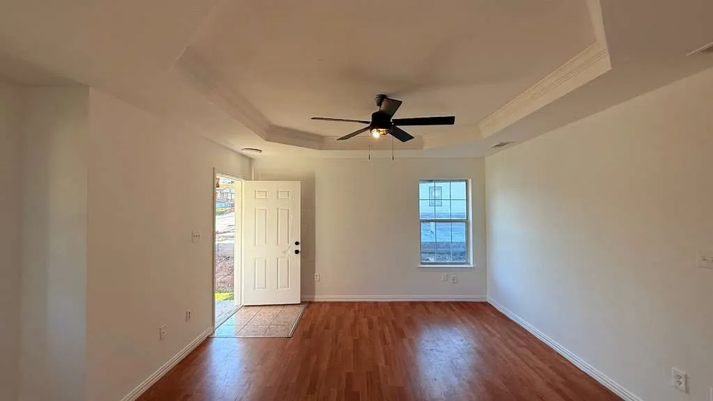 Entryway featuring a ceiling fan, crown molding, dark wood-type flooring, and a tray ceiling