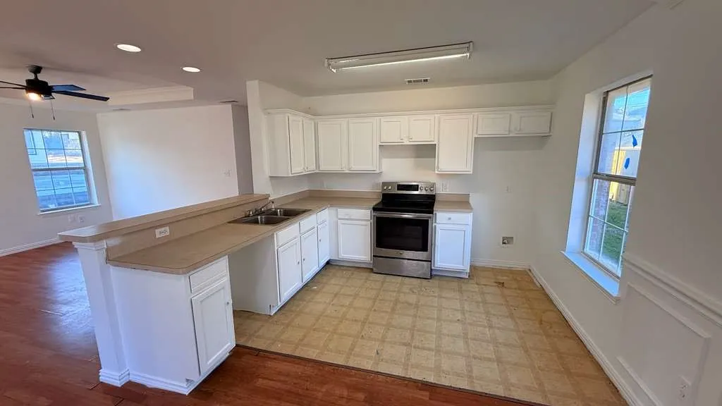 Kitchen with stainless steel range with electric stovetop, white cabinetry, light flooring, a ceiling fan, and light countertops