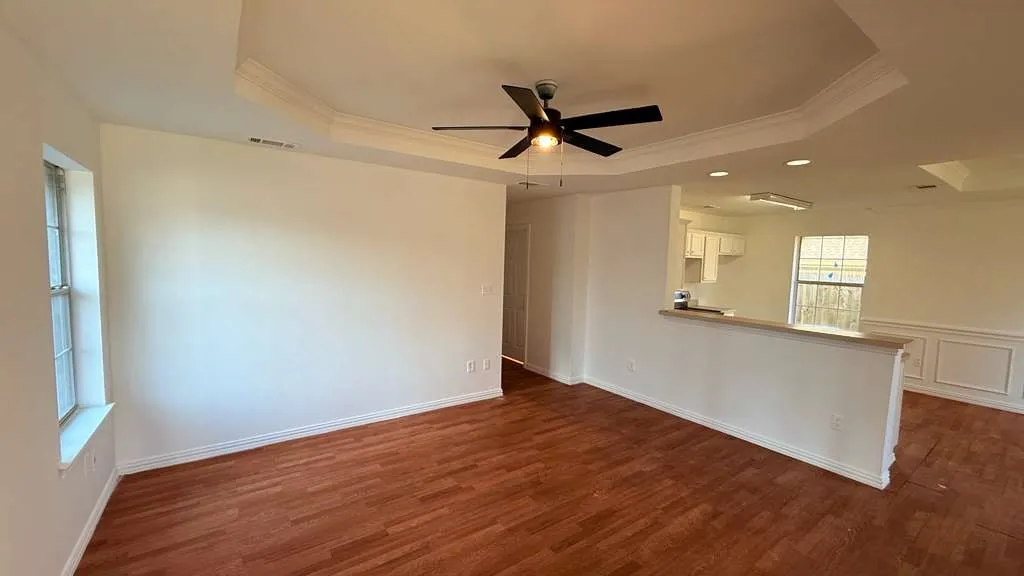 Spare room featuring crown molding, a ceiling fan, and dark wood-style floors
