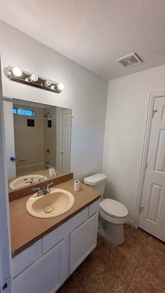 Bathroom featuring vanity, dark tile patterned floors, and a textured ceiling