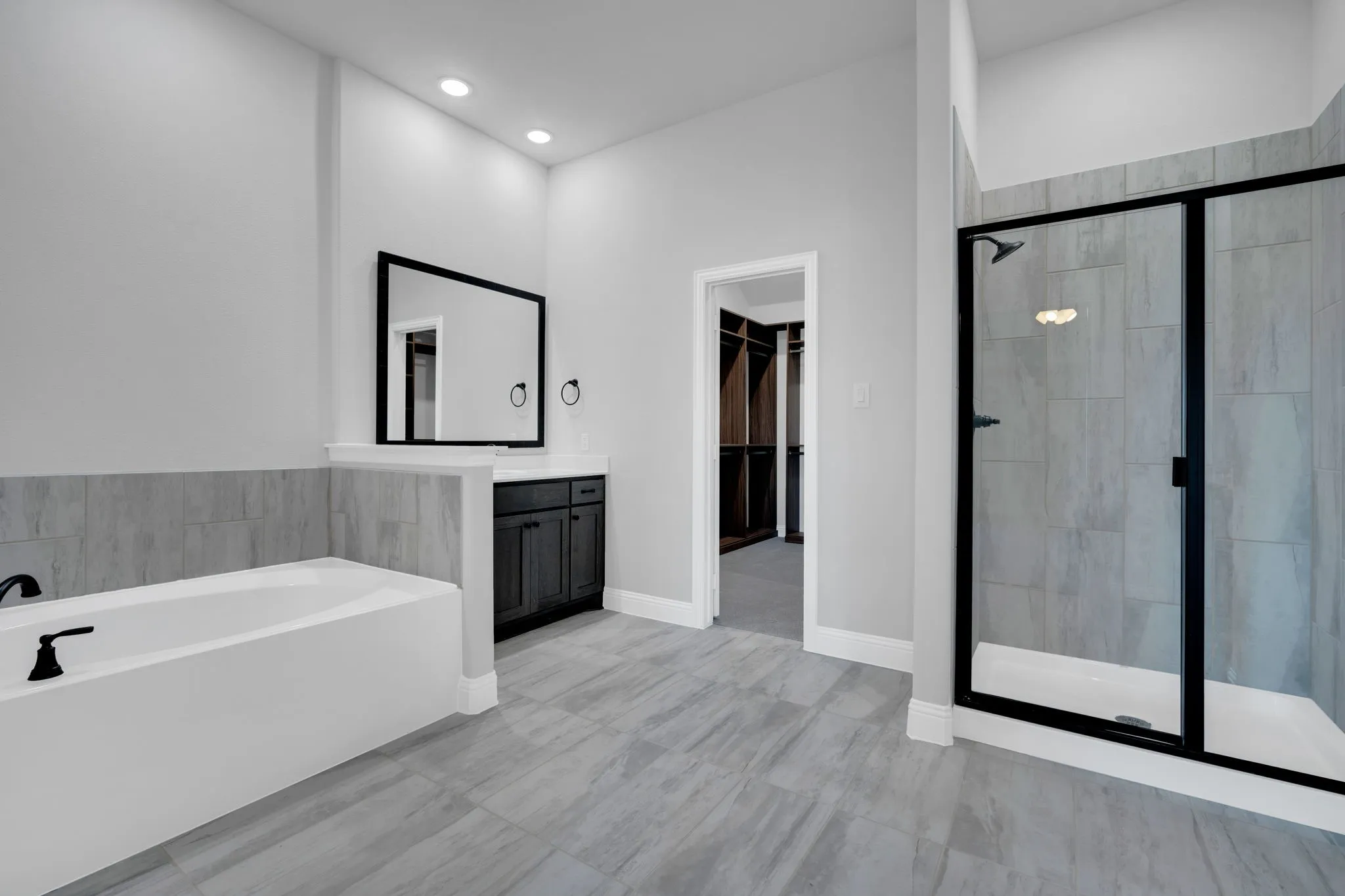Spa-inspired primary bath with soaking tub, dual vanities, and oversized walk-in shower with modern tile finishes.