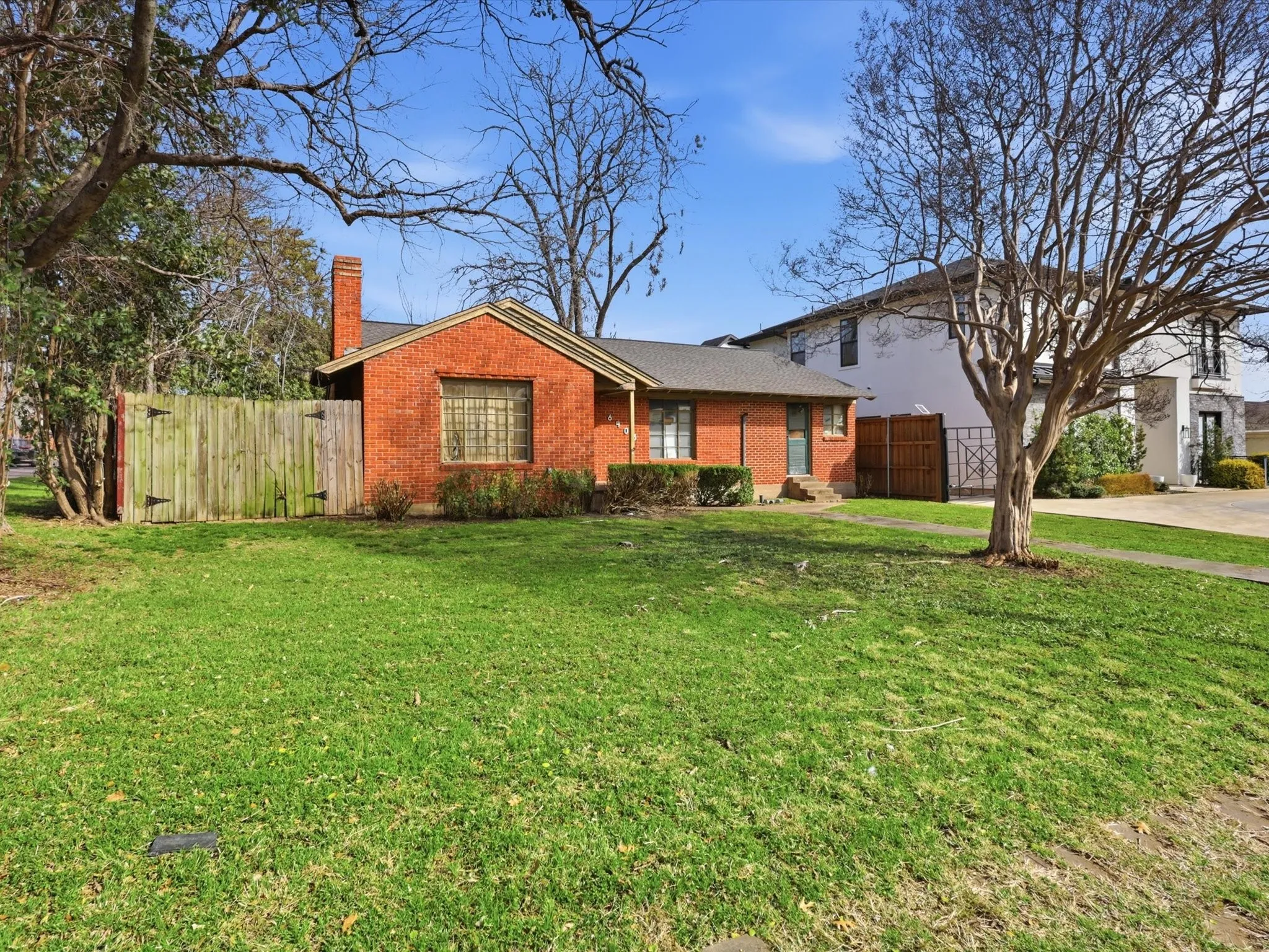 View of front of home with brick siding, a chimney, and driveway