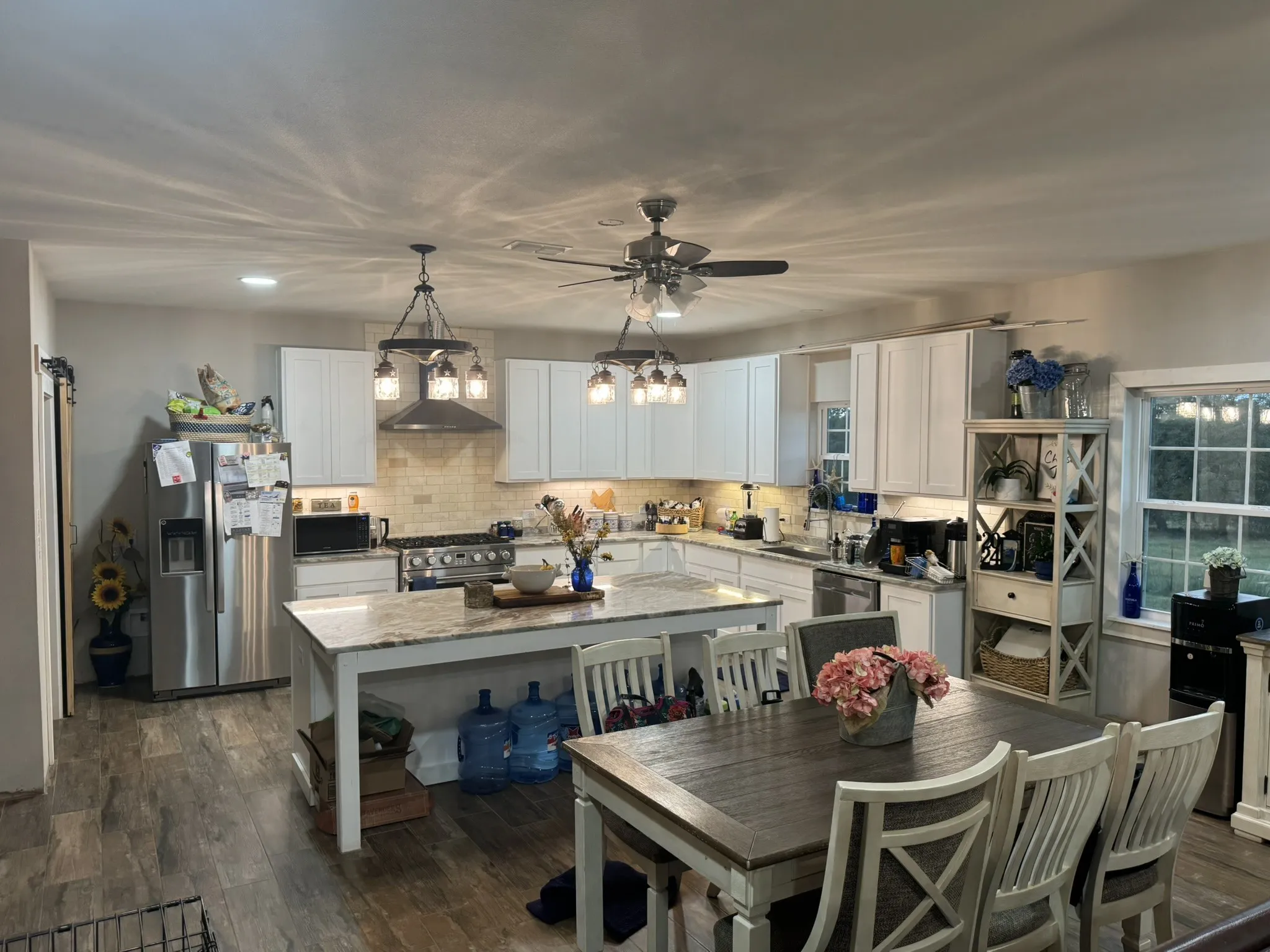 Kitchen featuring stainless steel appliances, light stone countertops, decorative backsplash, white cabinetry, and pendant lighting