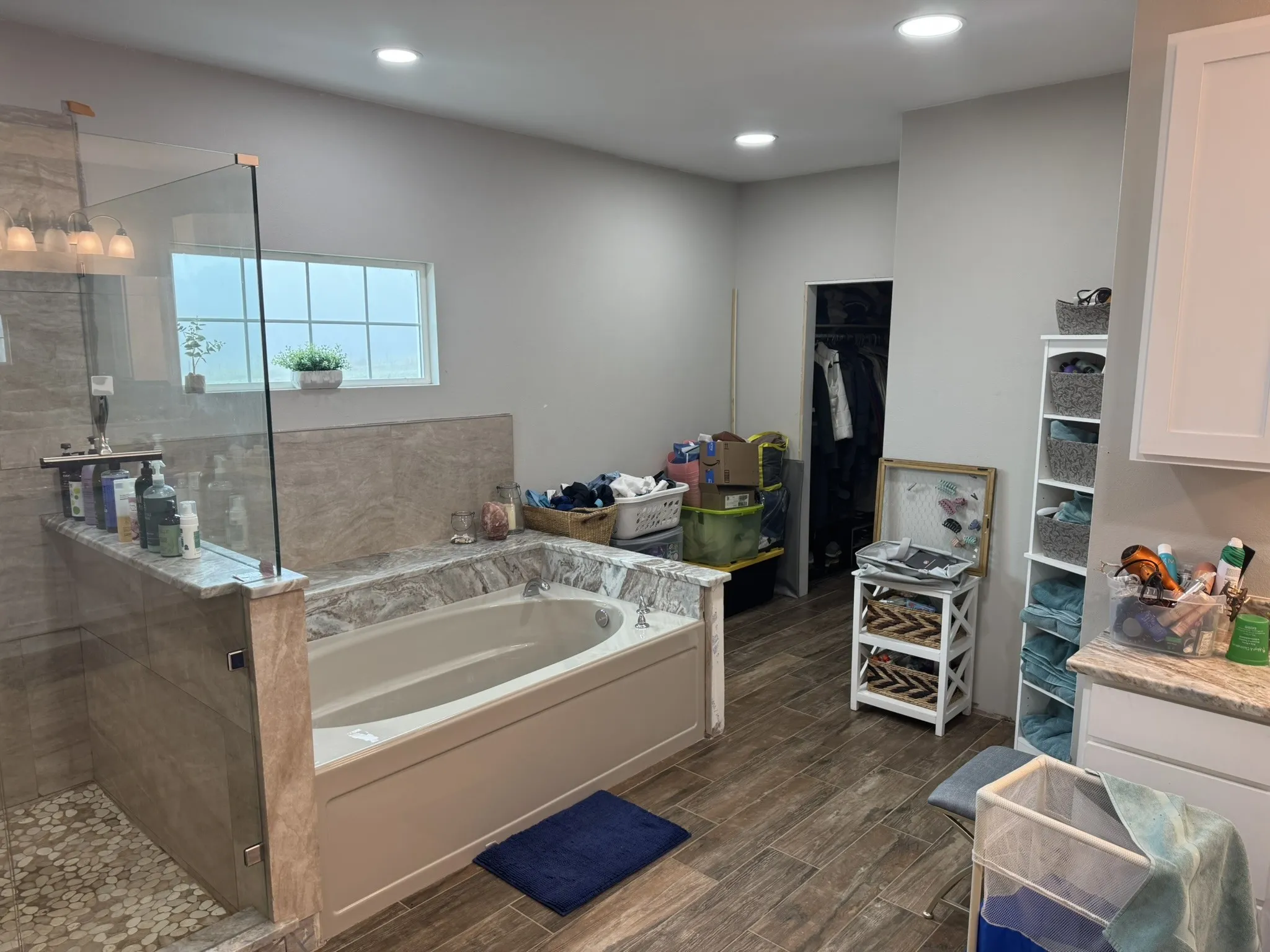 Full bath with a spacious closet, walk in shower, a garden tub, wood tiled floors, and recessed lighting