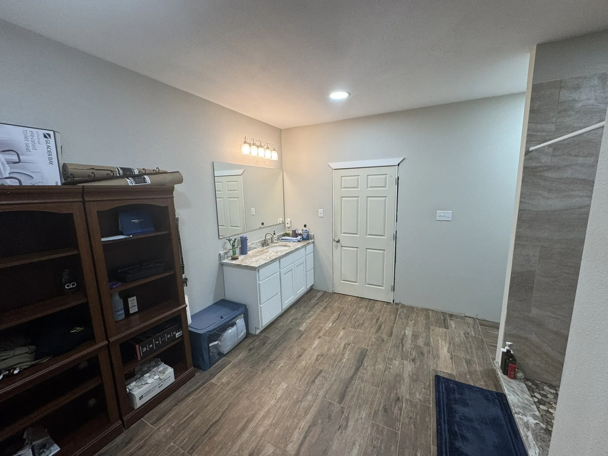 Full bathroom with dark wood finished floors, vanity, tiled shower, and recessed lighting