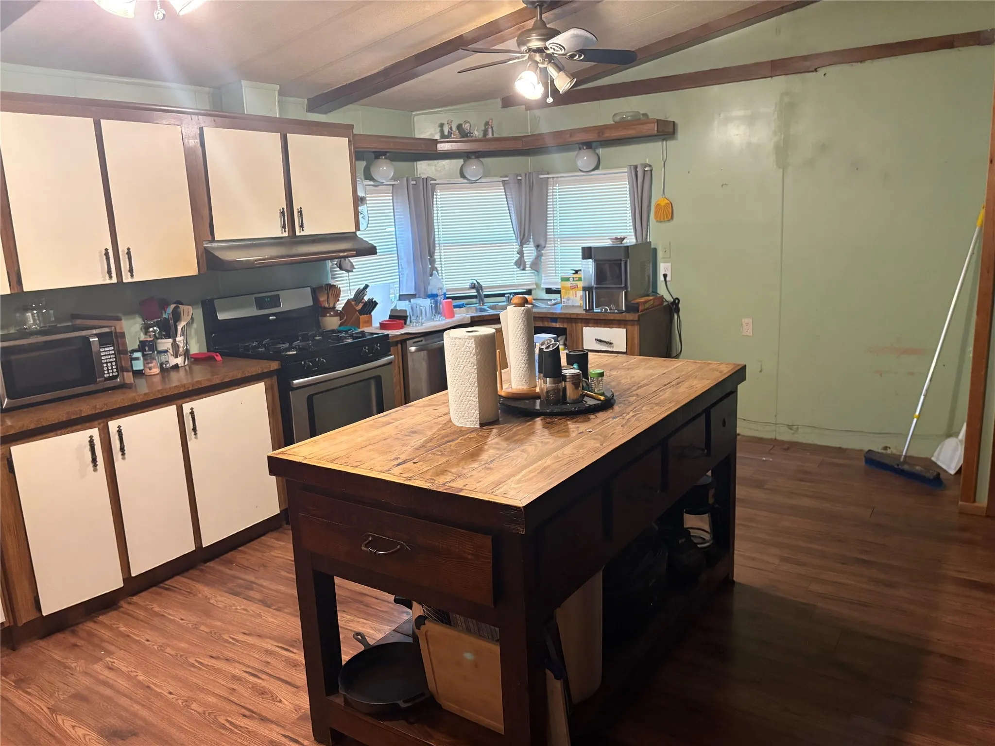 The kitchen features a functional layout with wood-toned cabinetry, light-colored upper cabinets, and a central island with a wood countertop