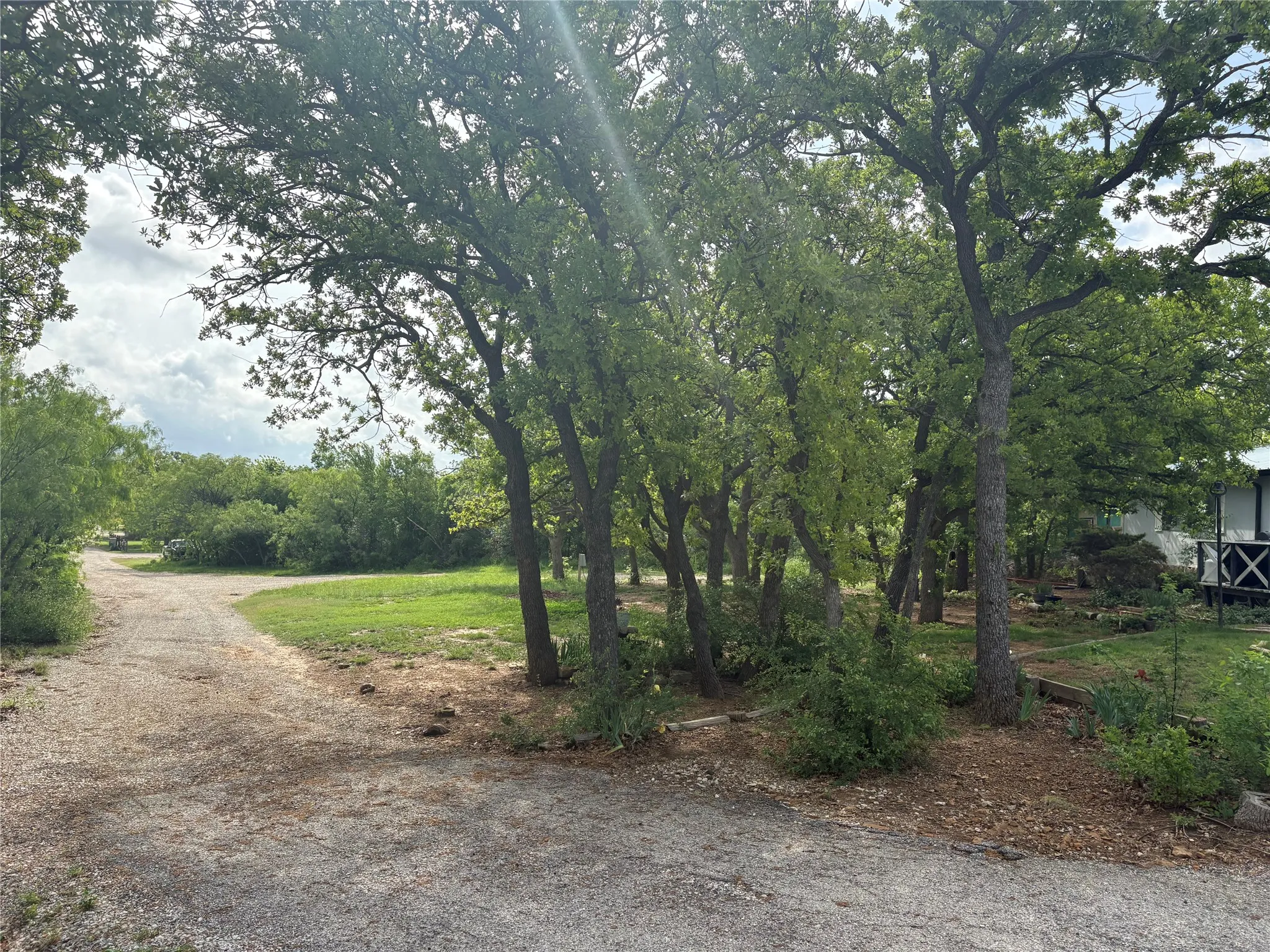 The property features mature trees and a gravel path, surrounded by natural landscaping