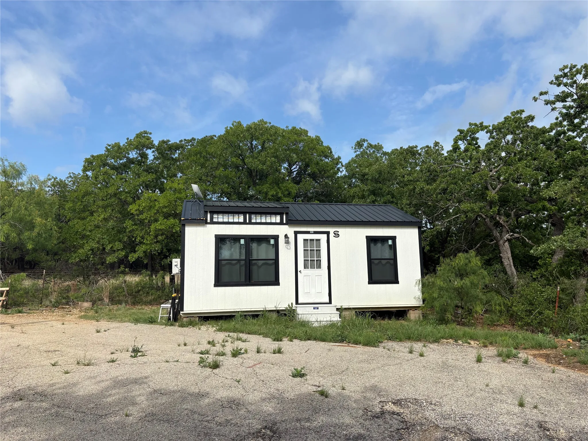 The property features a white exterior with black trim windows and a black metal roof