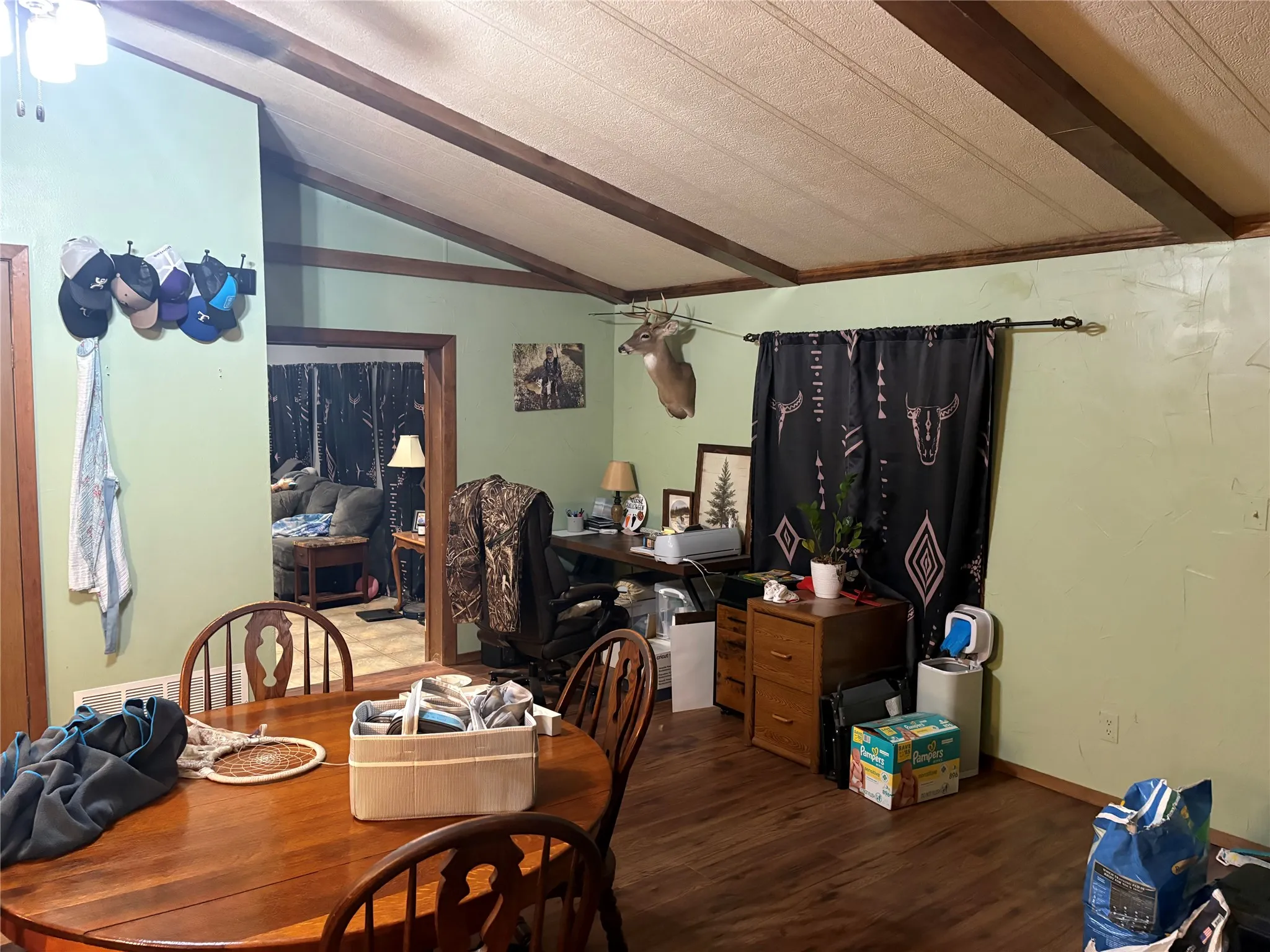Dining area featuring dark wood-style floors, a ceiling fan, and beamed ceiling