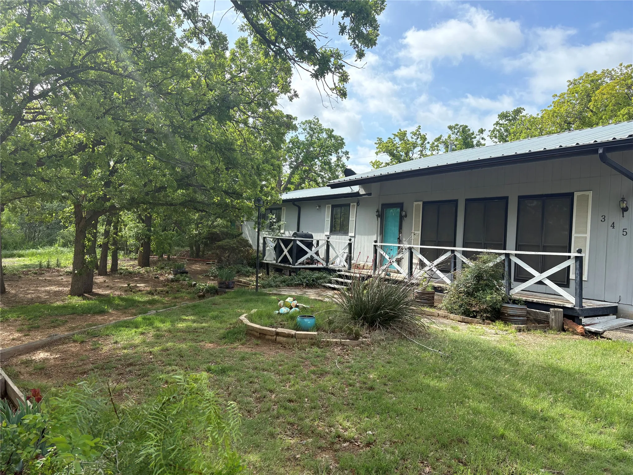 The property features a front porch with white railing, a turquoise entry door, and a metal roof
