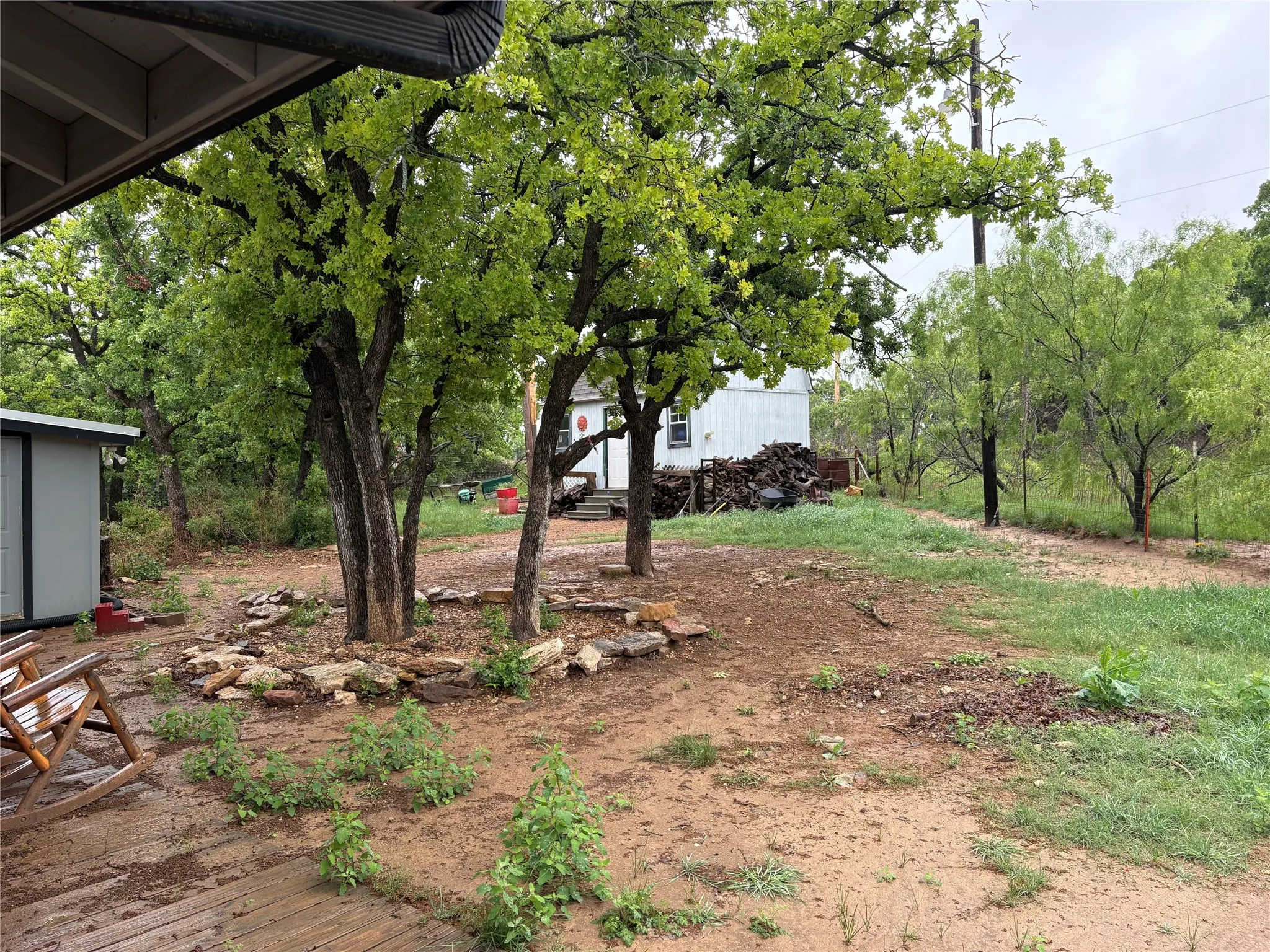 Expansive outdoor space featuring mature trees and a stone-lined planter bed