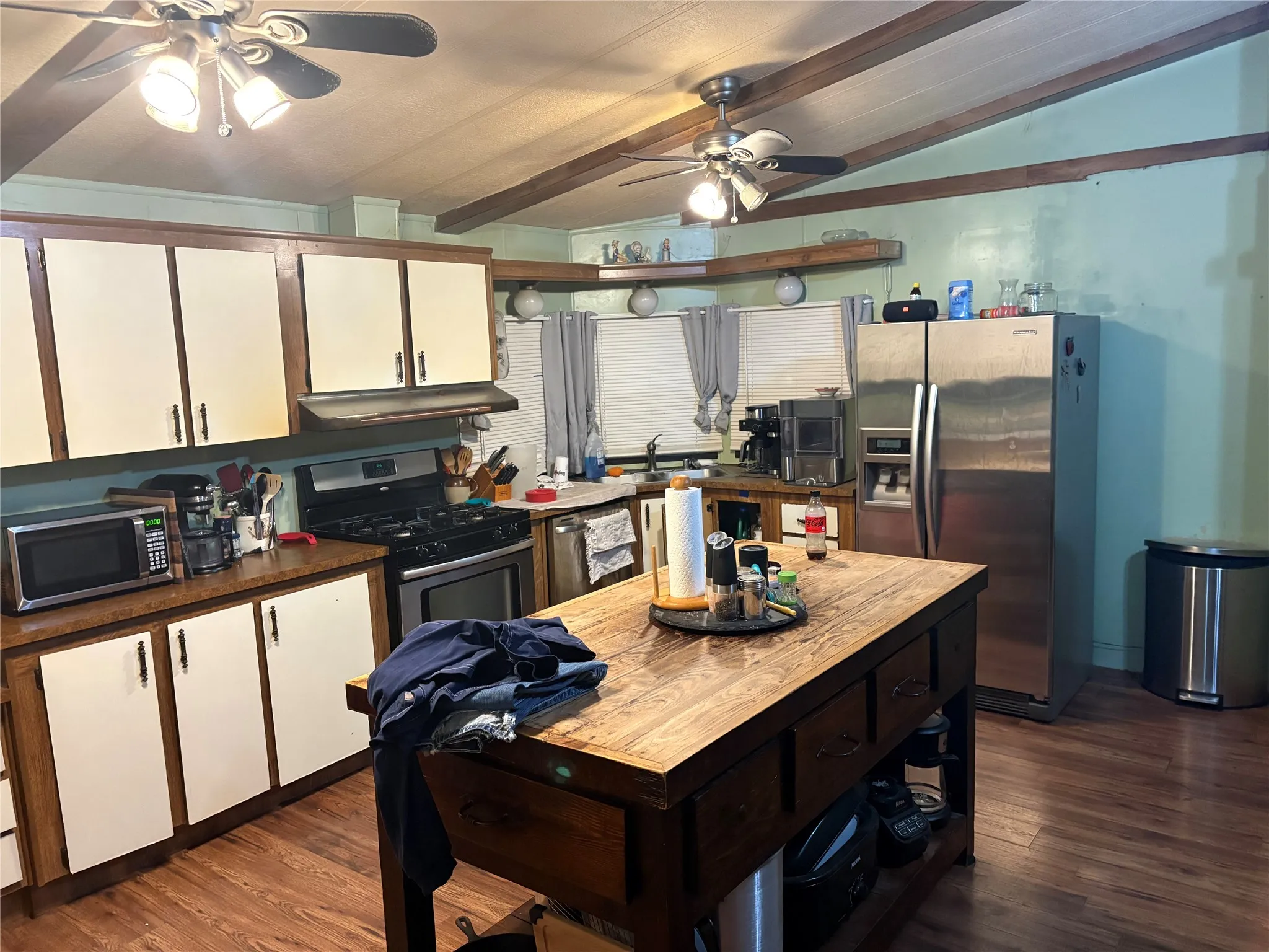 Two tone kitchen with stainless steel appliances, a ceiling fan, dual tone cabinets, dark wood-style flooring, and open shelves