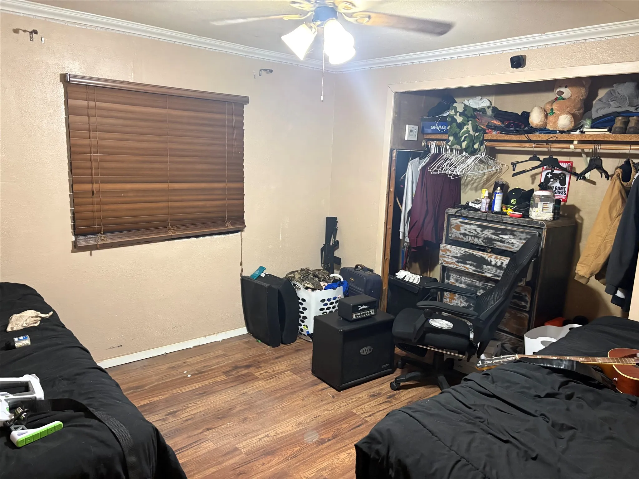 Bedroom with dark wood-style floors, a closet, crown molding, and a ceiling fan
