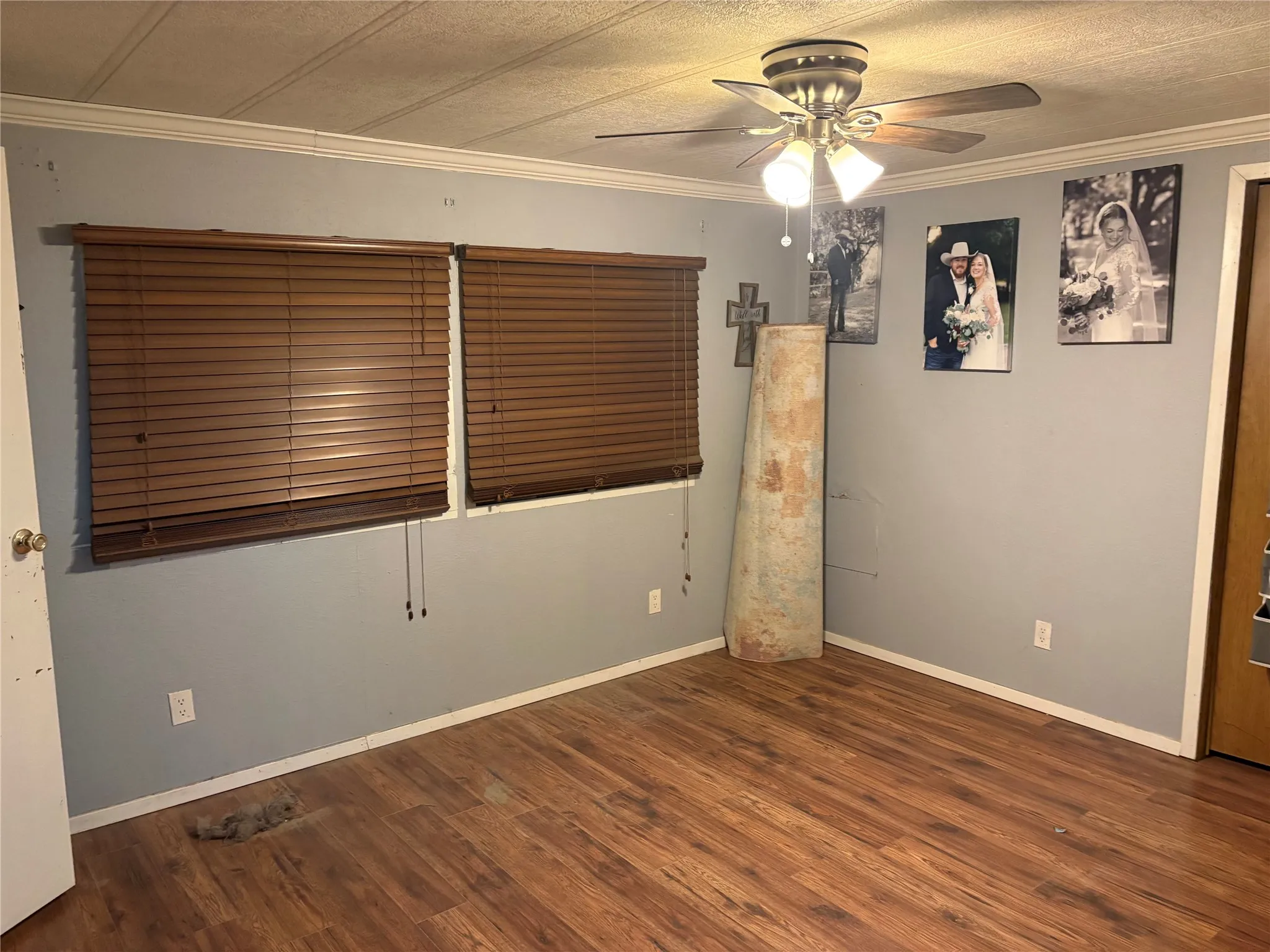 Empty room with ceiling fan, dark wood-style floors, and crown molding