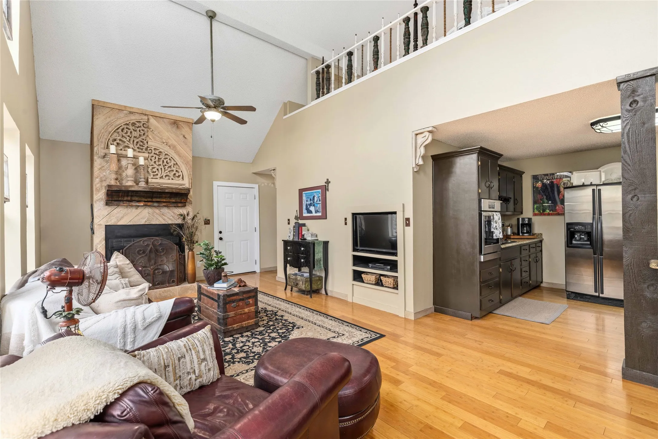 Living area featuring light wood-type flooring, a ceiling fan, a fireplace, and lofted ceiling