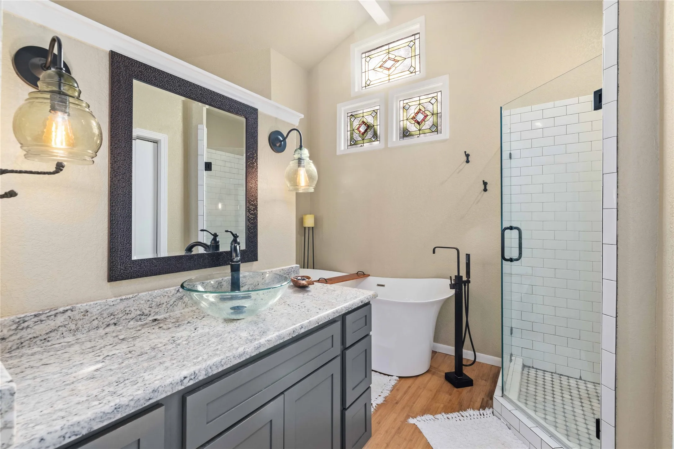 Bathroom featuring a shower stall, vanity, a freestanding tub, and light wood finished floors