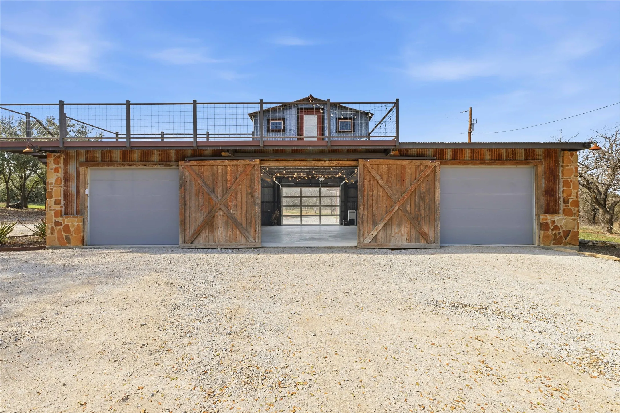 View of front of home featuring stone siding, a garage, driveway, and an outbuilding