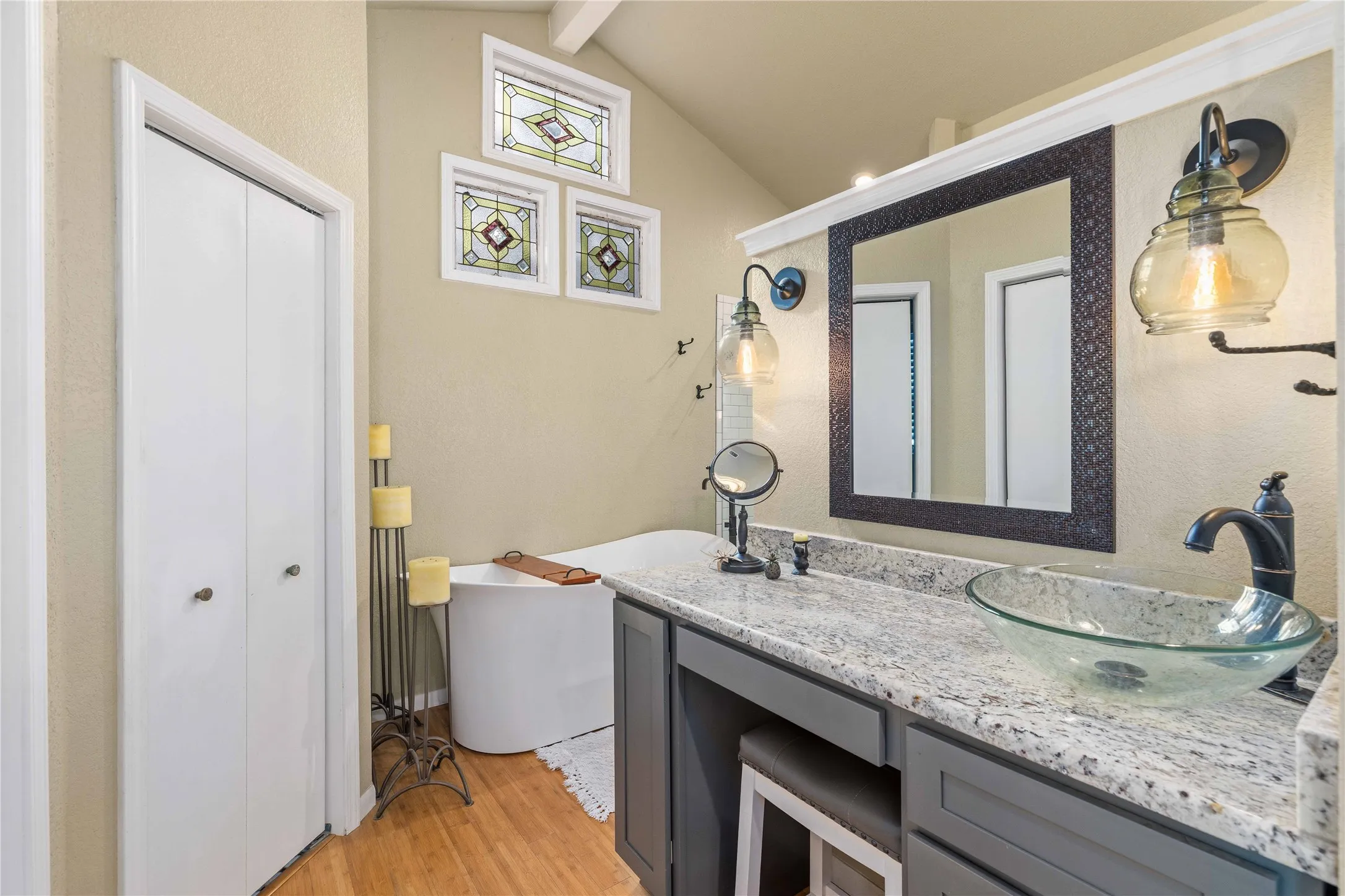 Bathroom with double vanity, light wood-style flooring, a freestanding bath, and beam ceiling