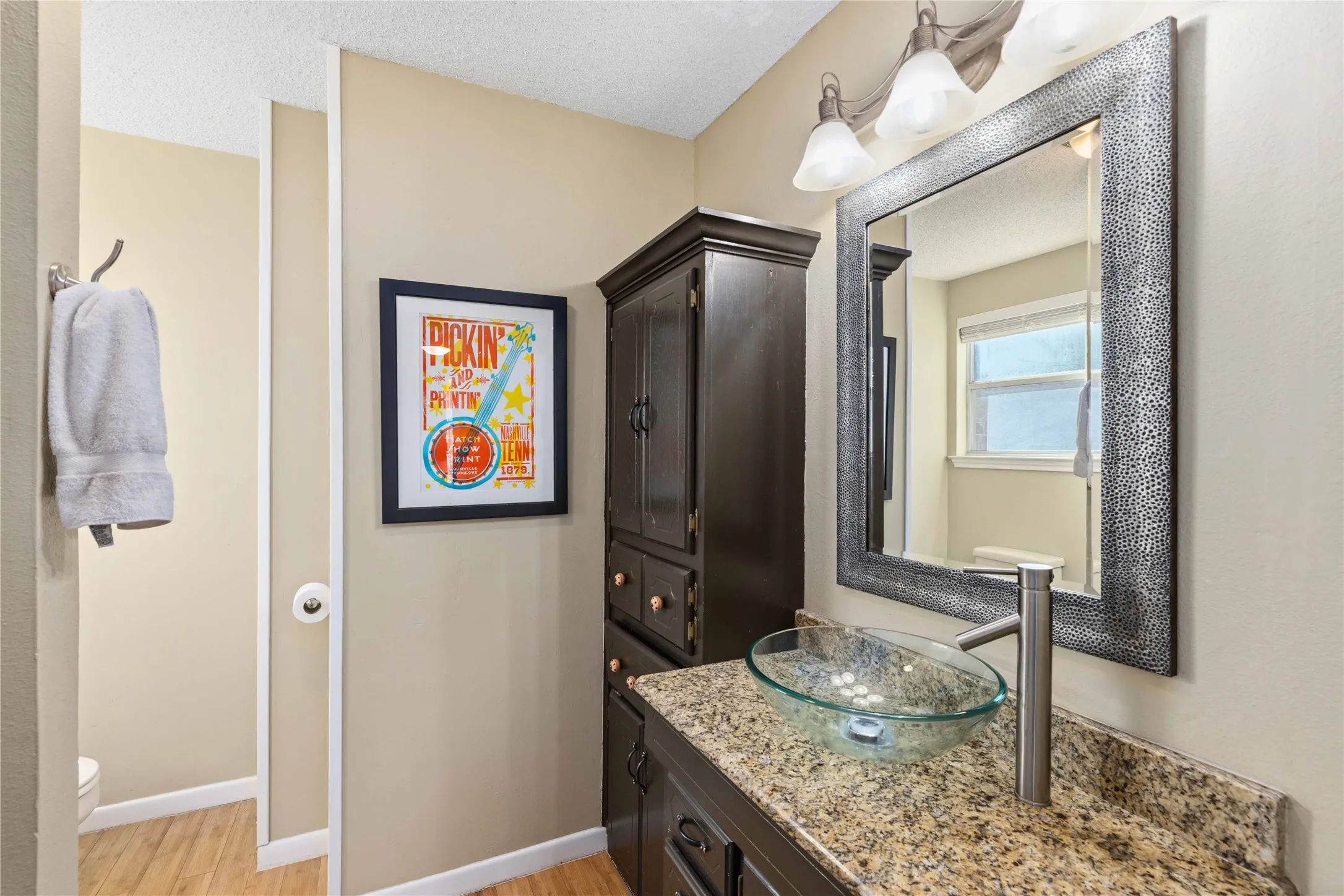Bathroom with vanity, light wood-style flooring, and a textured ceiling