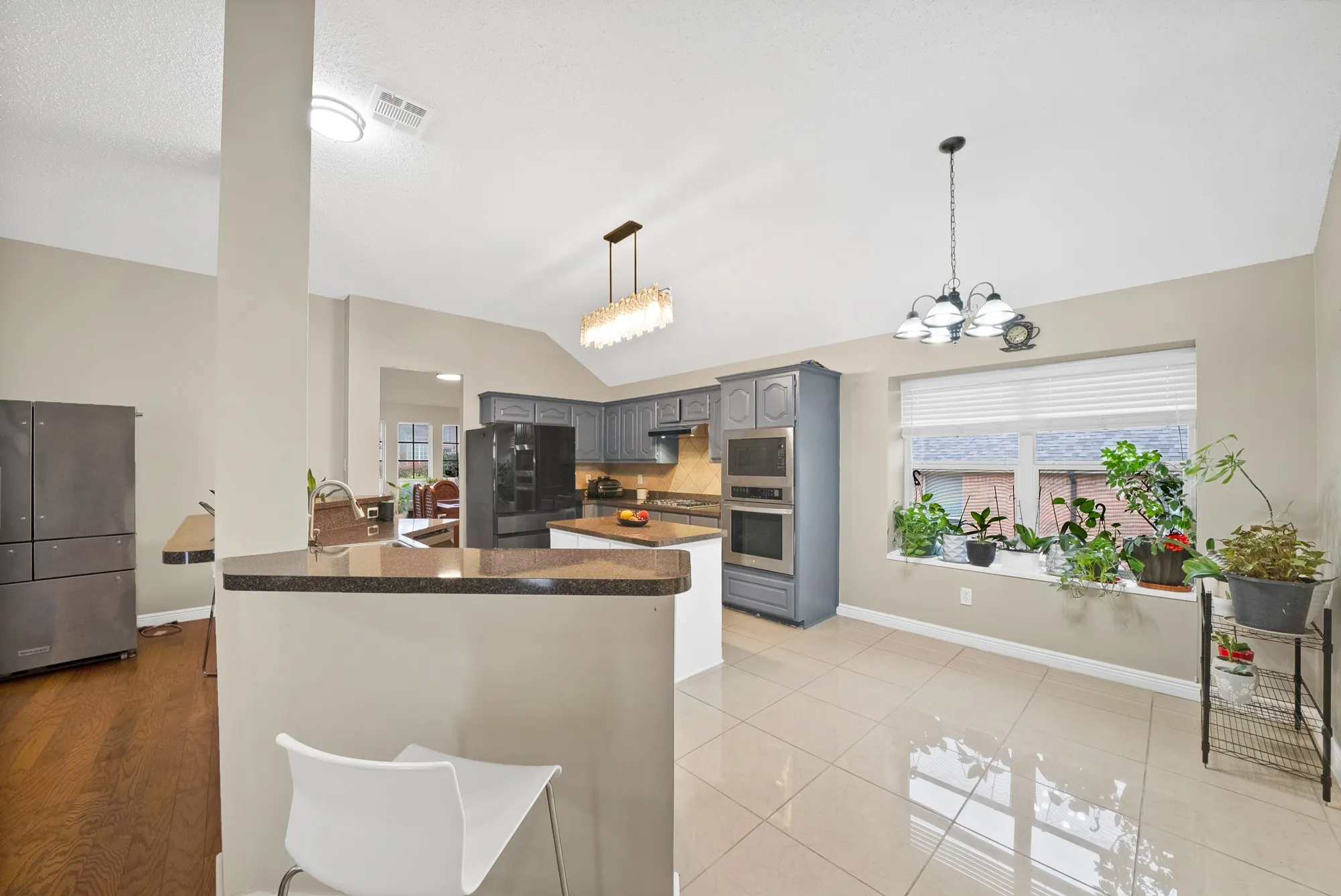 Kitchen with stainless steel appliances, lofted ceiling, suspended lighting, a peninsula, and gray cabinets