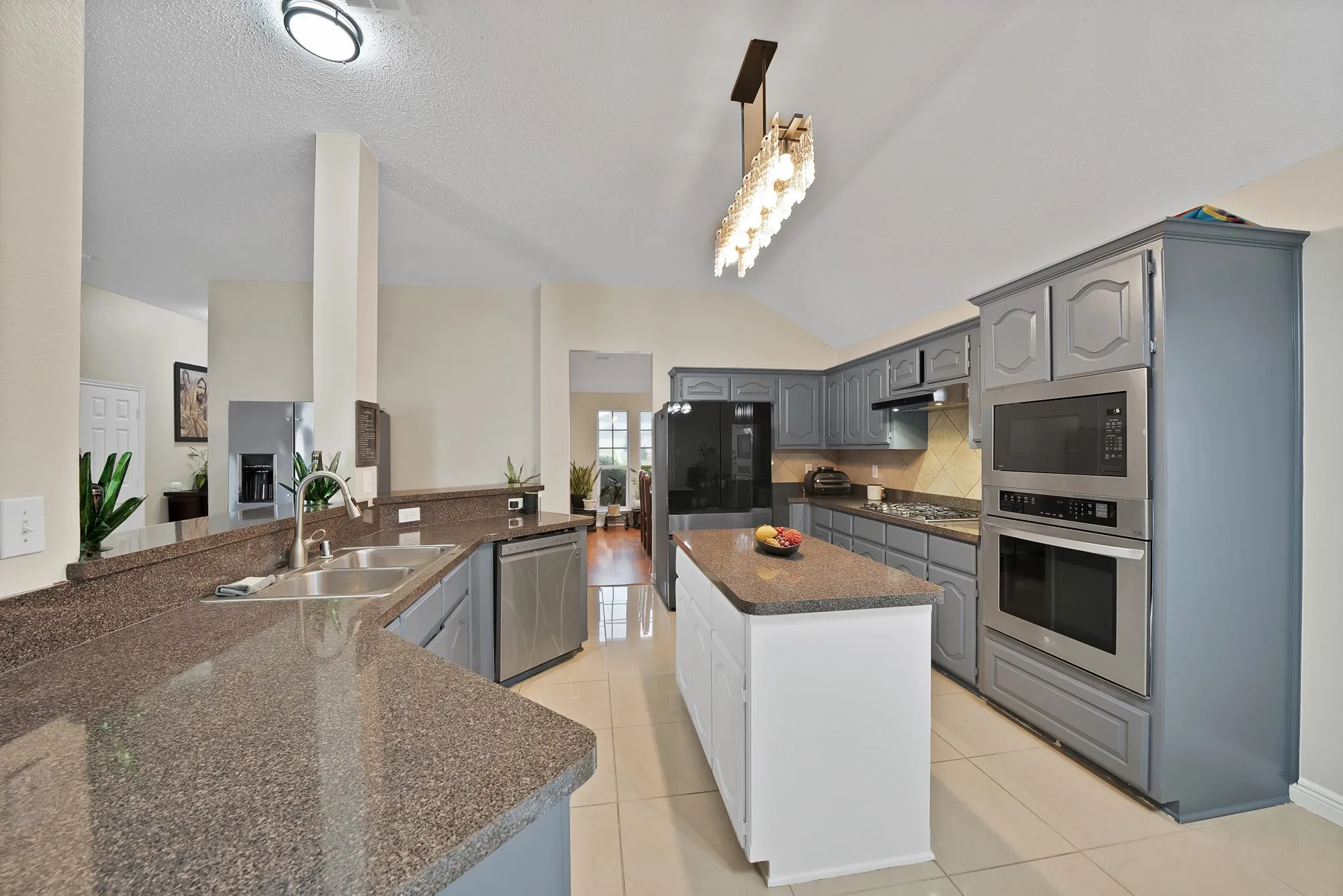 Kitchen featuring a center island, gray cabinets, stainless steel appliances, decorative backsplash, and vaulted ceiling