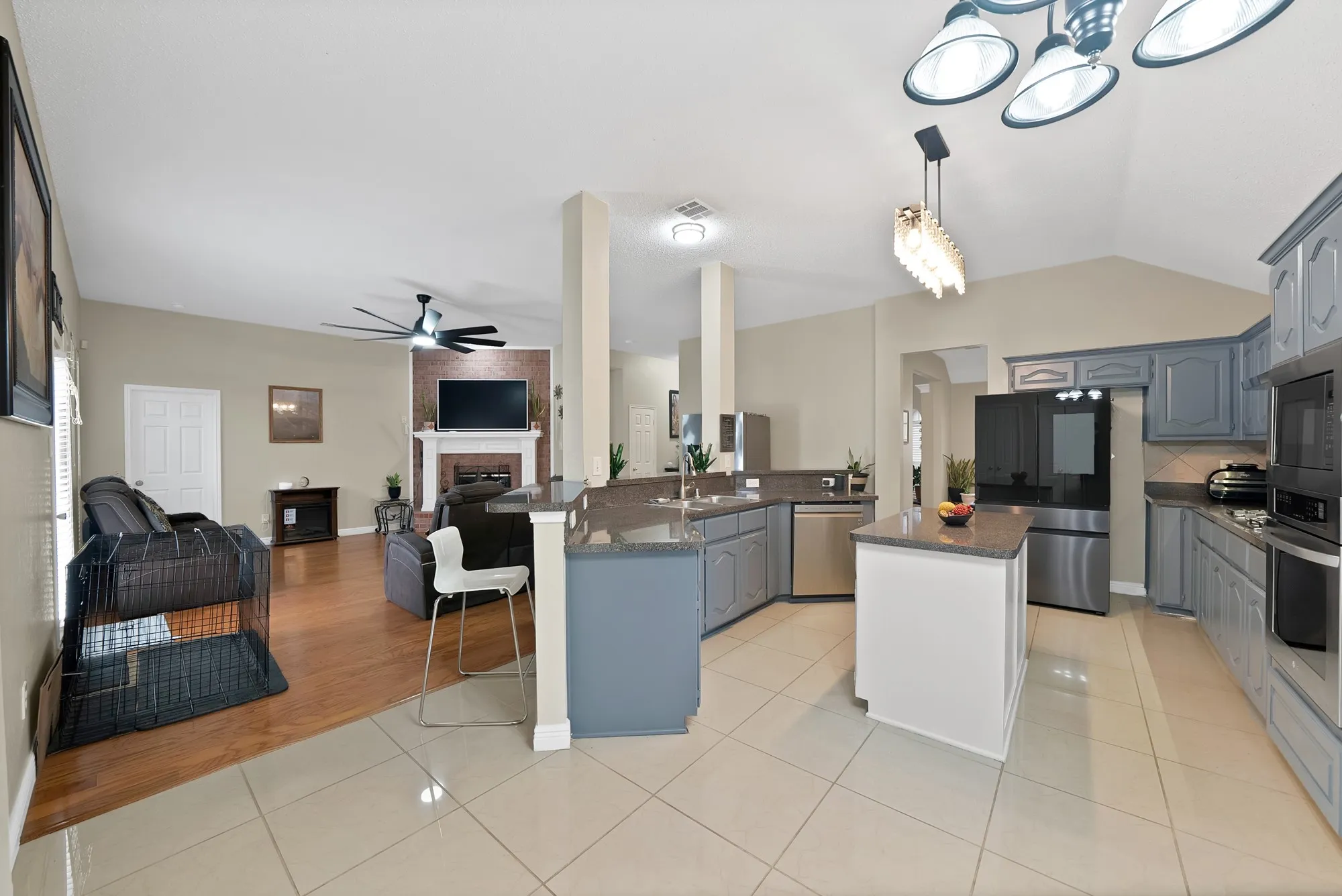 Kitchen featuring a kitchen island, open floor plan, light tile patterned floors, stainless steel appliances, and a fireplace