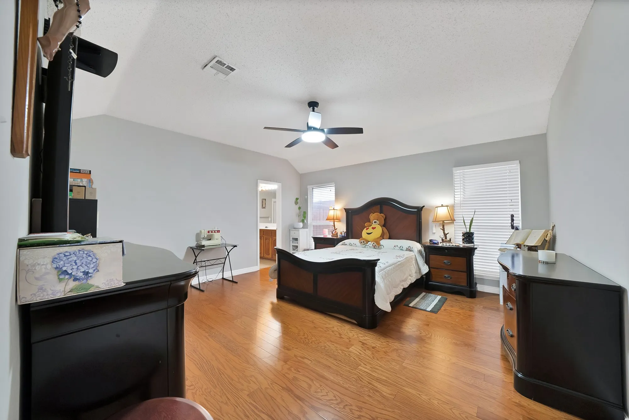 Bedroom with light wood-type flooring, a ceiling fan, and ensuite bath