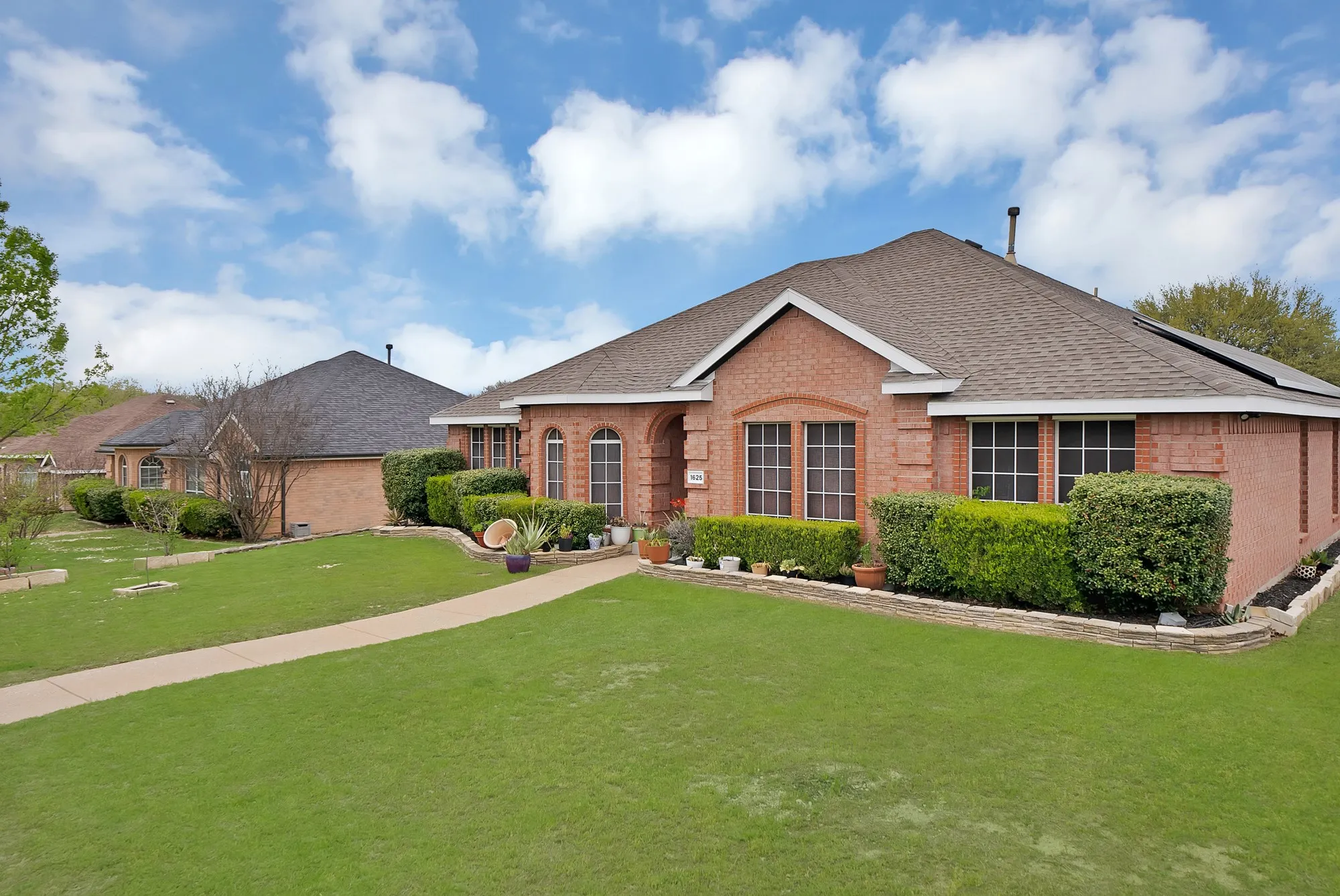 Ranch-style house with brick siding, a front lawn, and a shingled roof