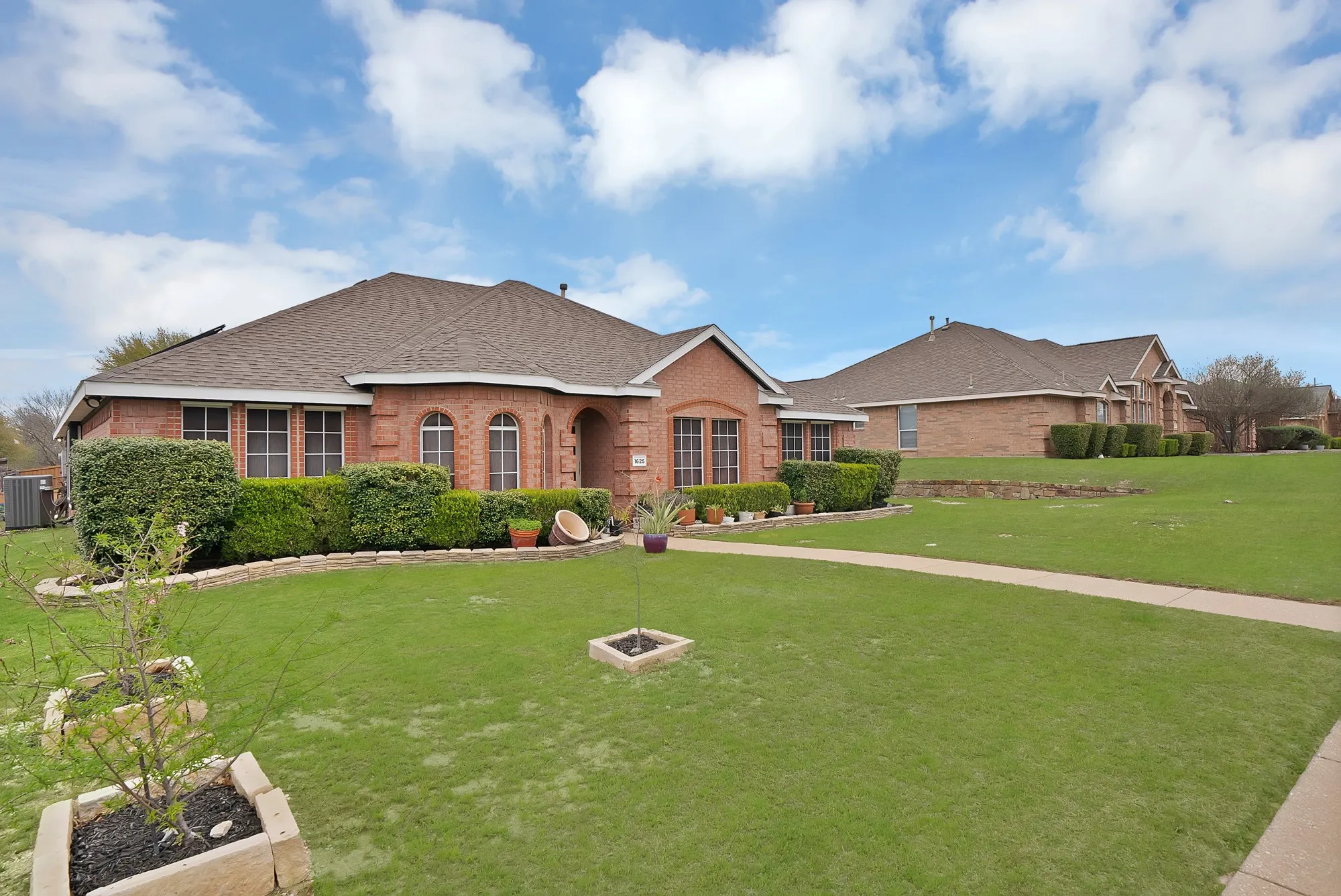 Ranch-style home with a front yard, brick siding, and roof with shingles