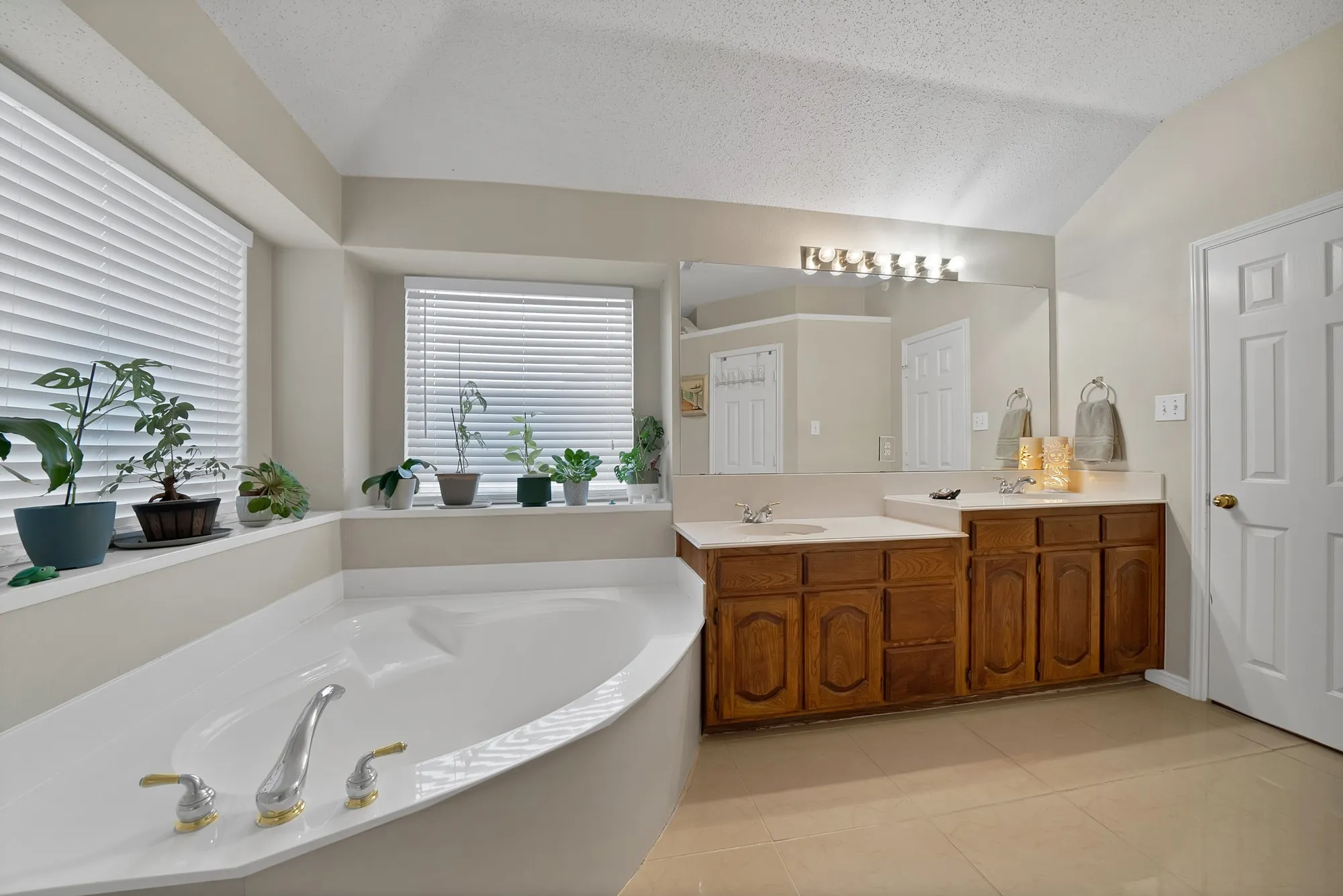Full bath featuring double vanity, a garden tub, and light tile patterned floors