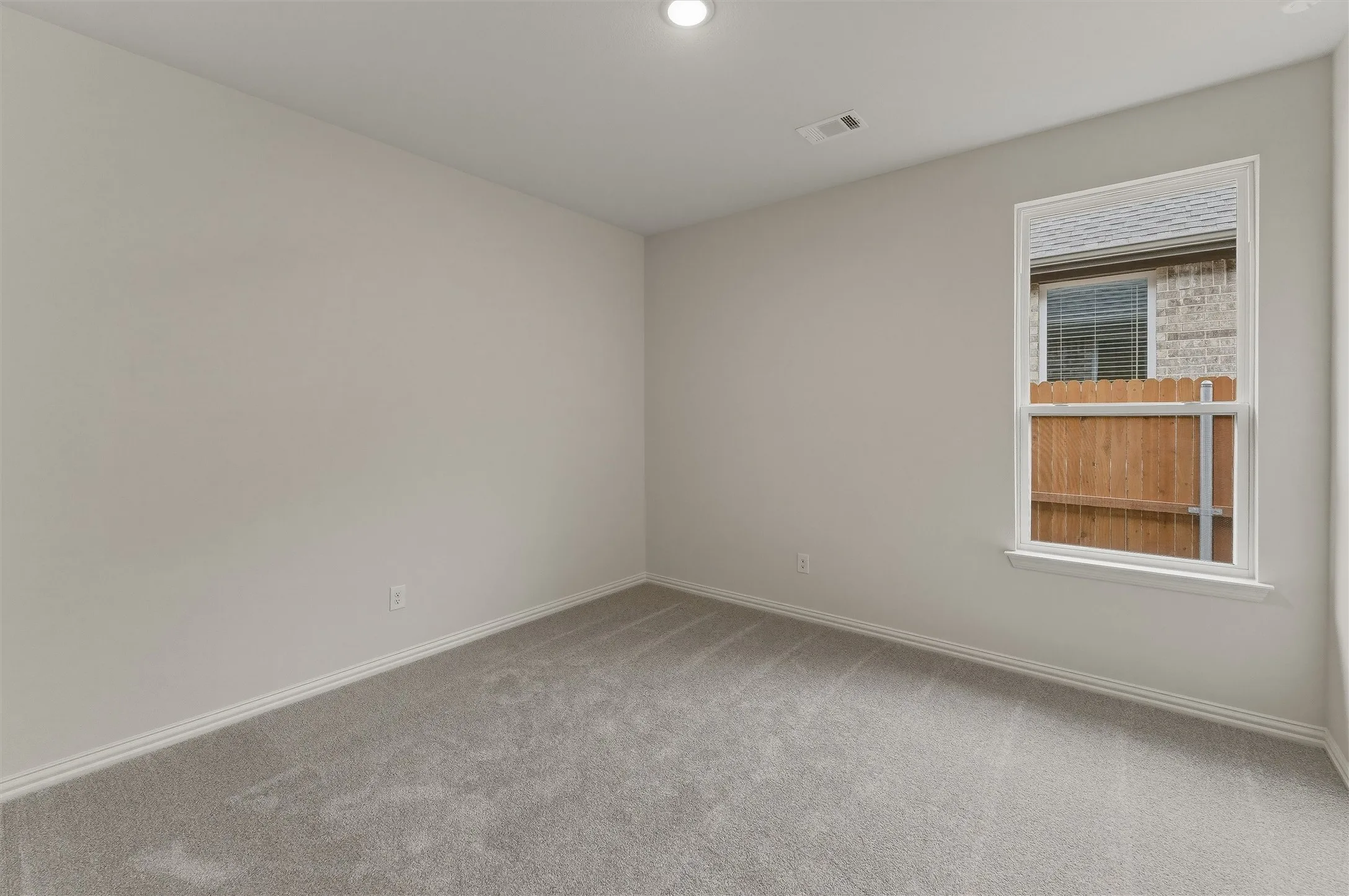 Light gray carpeted room with white baseboards and a recessed ceiling light