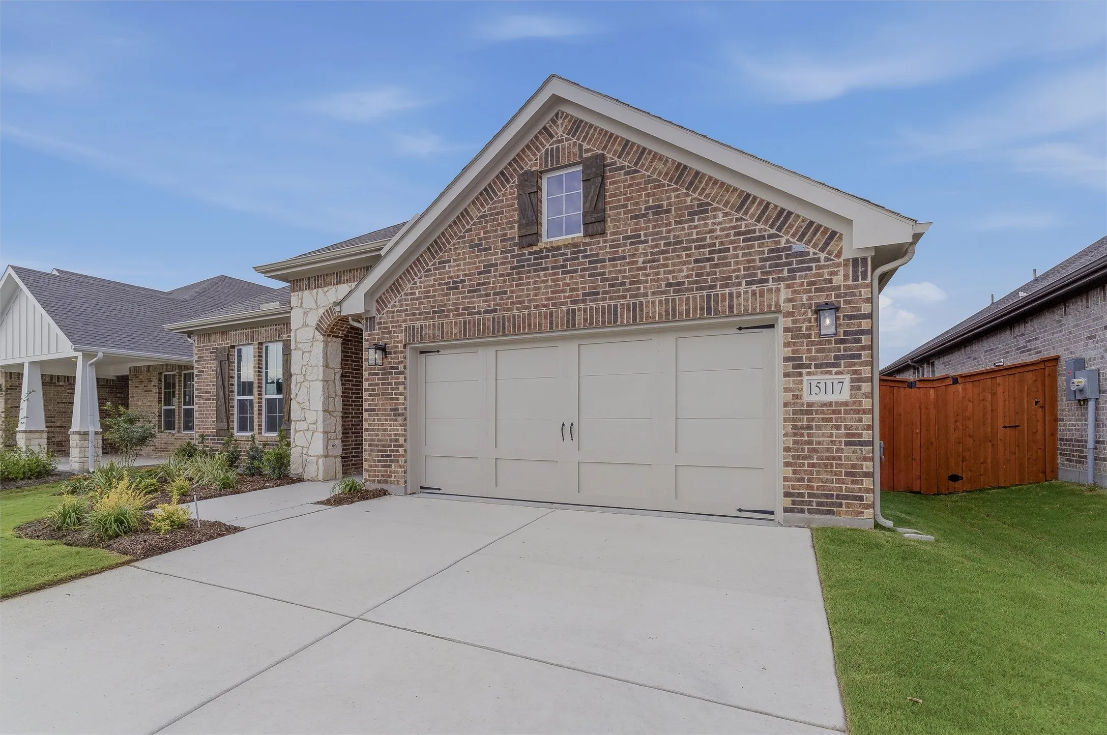 Brick and stone exterior featuring an attached two-car garage with a light-colored garage door
