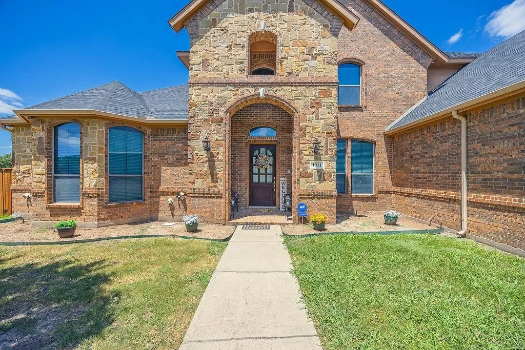 Doorway to property with a yard, brick siding, and stone siding