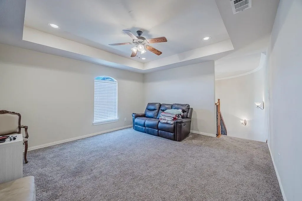 Living area with carpet, ceiling fan, recessed lighting, and a raised ceiling